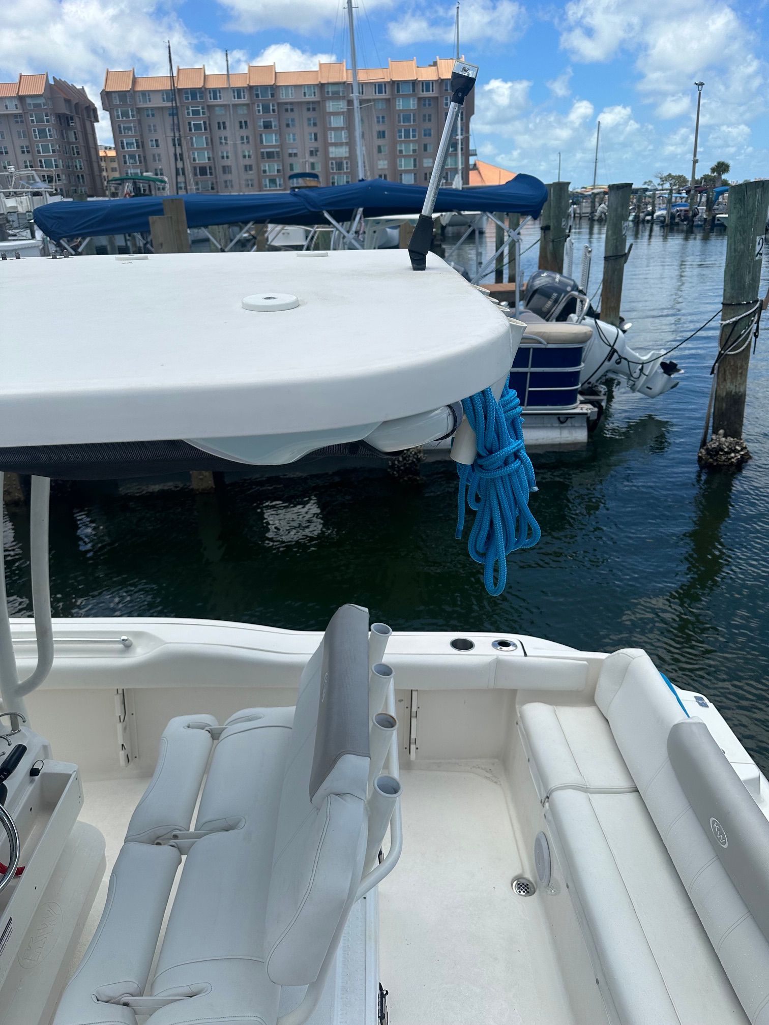 A Key West 219 FS boat docked in a marina, surrounded by other boats and buildings.