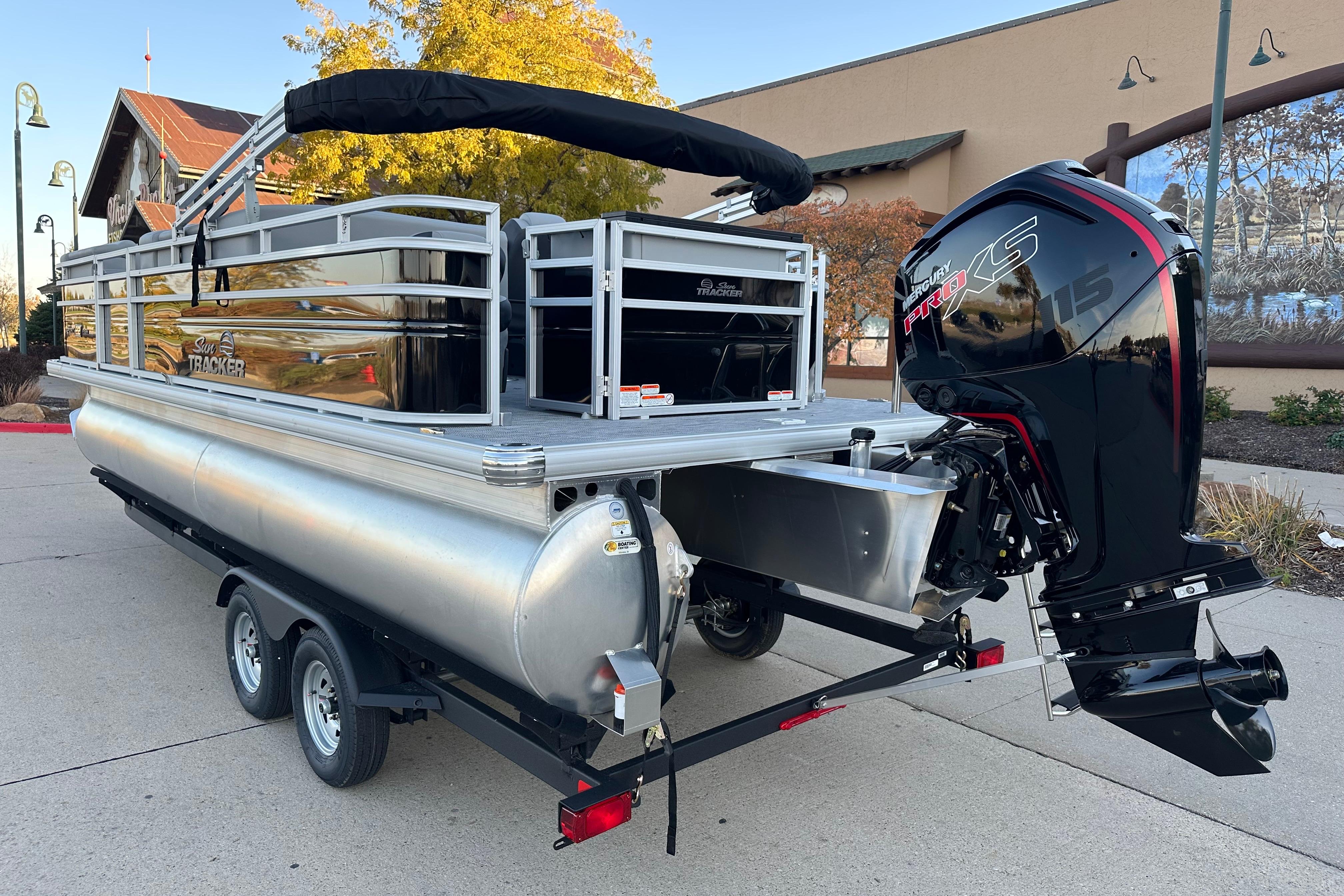 2026 Sun Tracker SportFish 22 DLX pontoon boat with powerful outboard motor on trailer.
