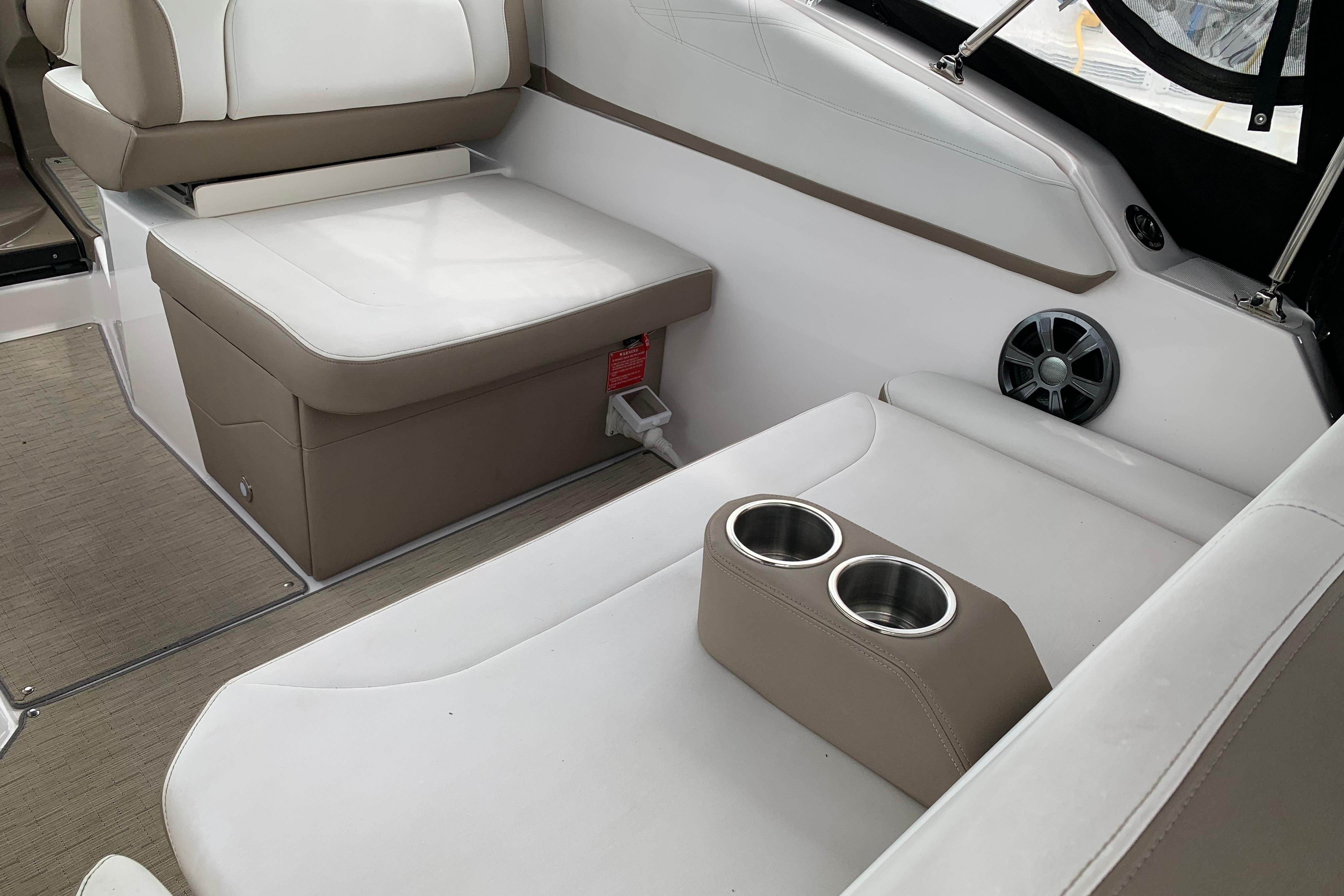 Interior of 2017 Regal 26 Express boat with beige and white seating, cup holders, and speaker.