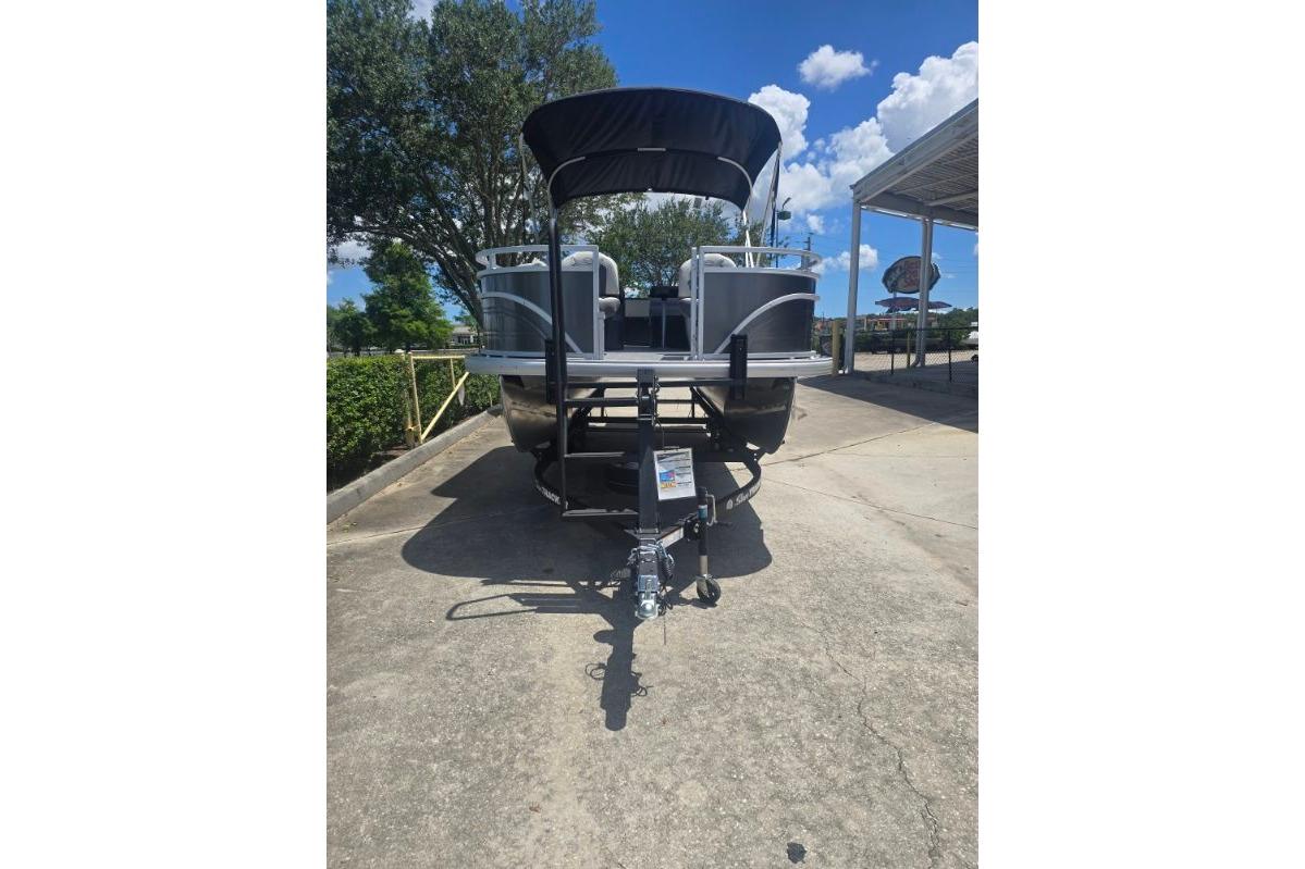 2026 Sun Tracker Fishin' Barge 22 DLX pontoon boat on trailer, parked outdoors.