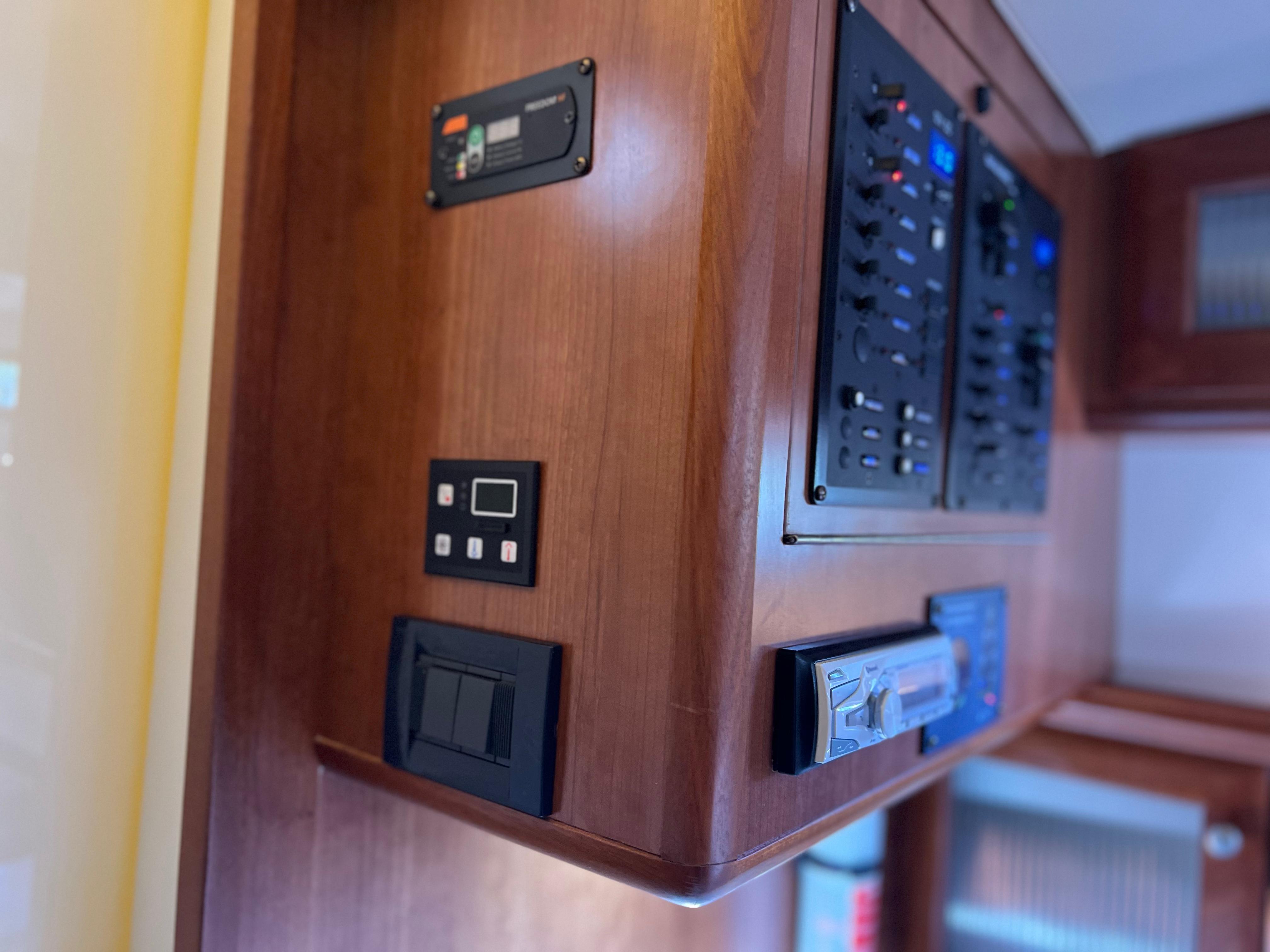 Control panel inside 2016 Marlow Pilot 31 Pilot boat, featuring wooden cabinetry and electronic displays.