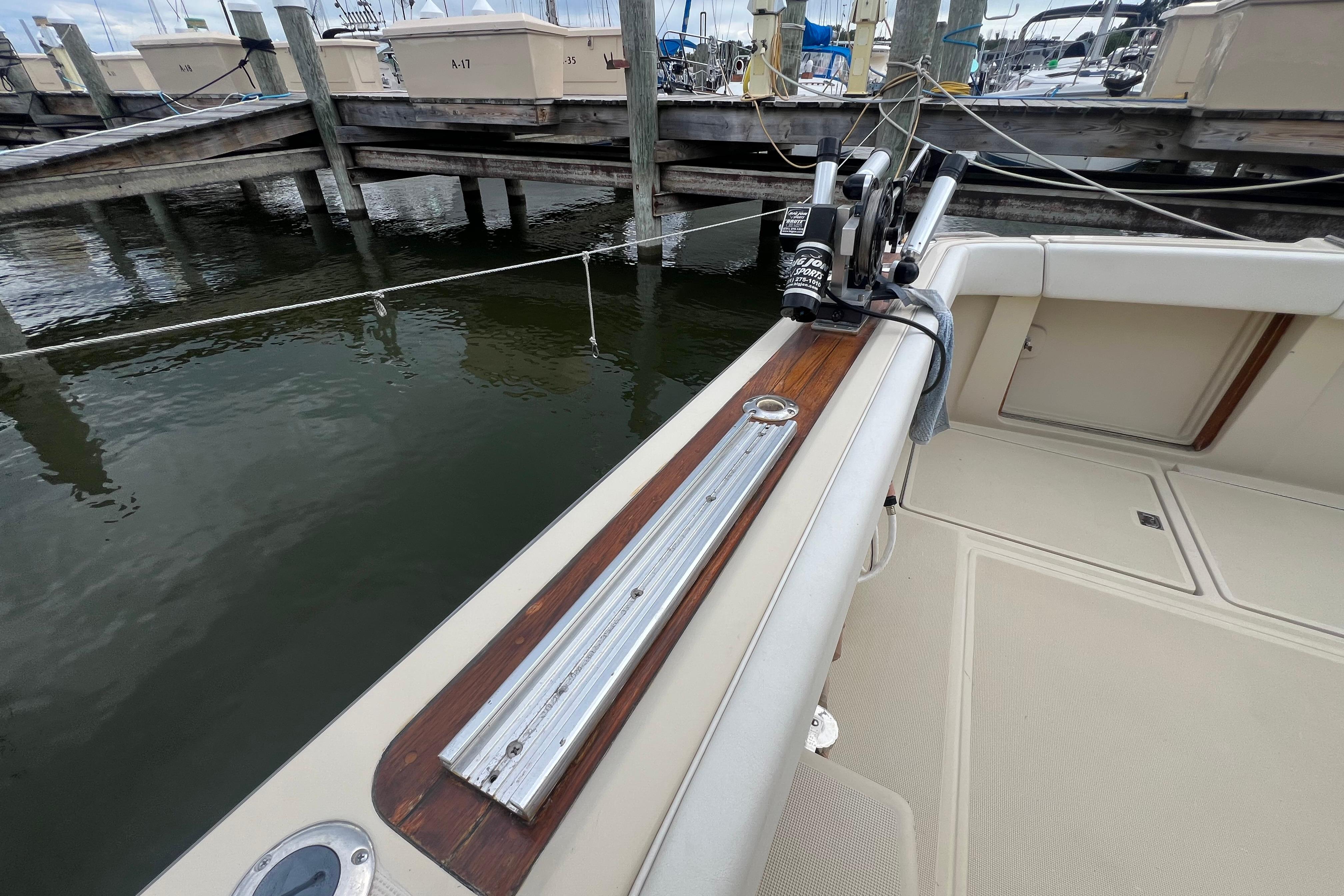 1985 Tiara 36 OPEN boat docked, featuring a wooden rail and fishing equipment.