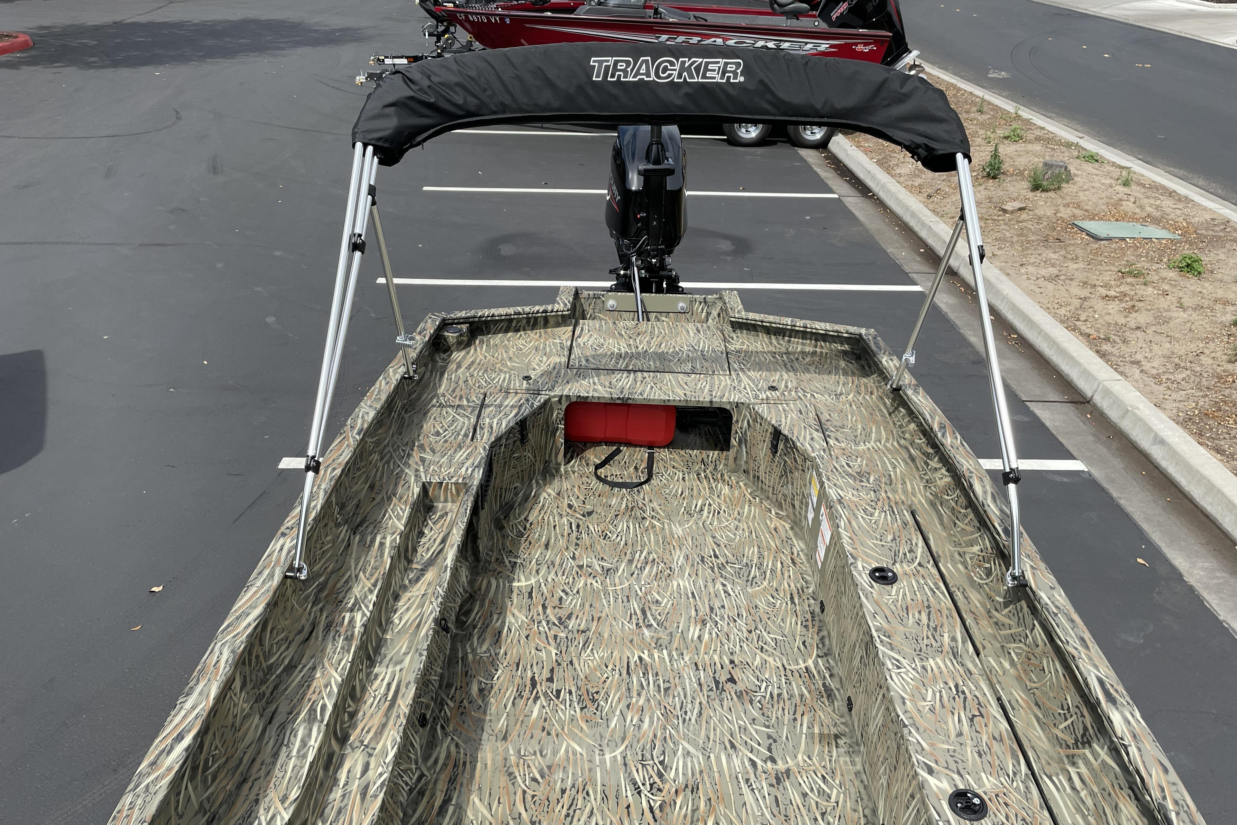 2026 Tracker Grizzly 1756 T Marsh boat with camouflage design and canopy in parking lot.