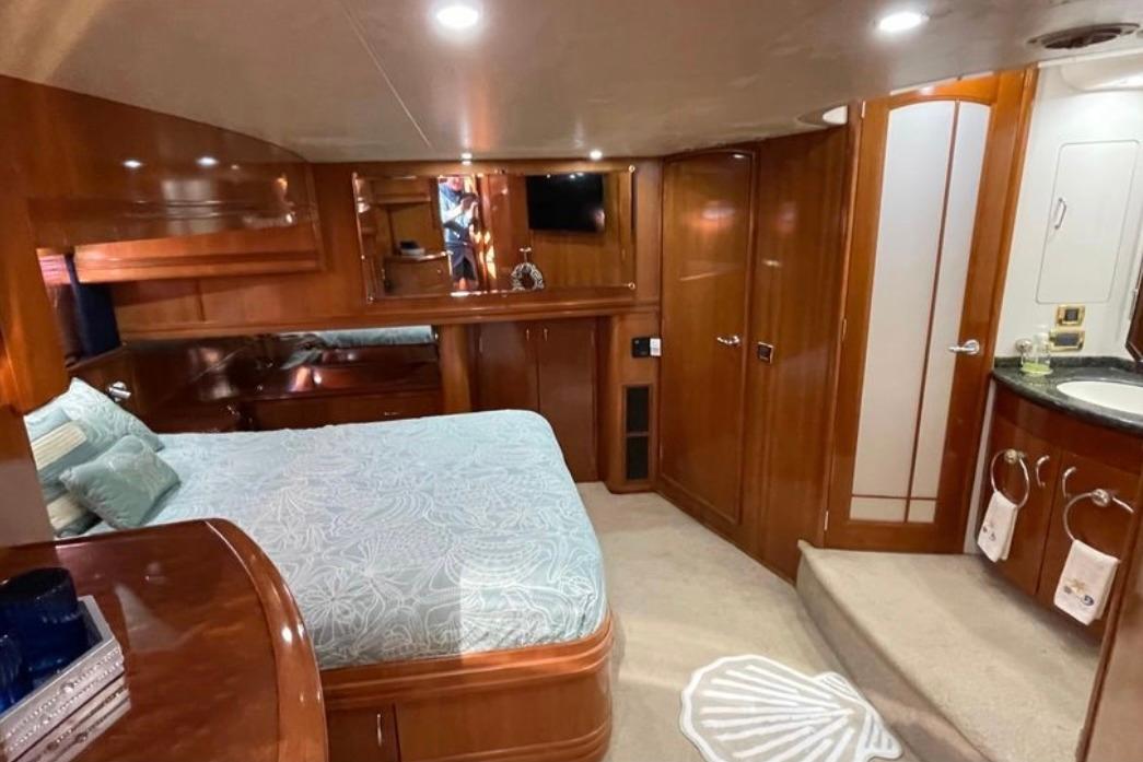 Luxurious 2005 Carver 56 Voyager yacht bedroom with elegant wood finishes and cozy bedding.