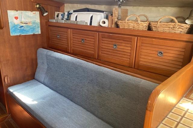 Interior of 1988 Westerly Corsair 36 sailboat with wooden cabinets and blue cushioned seating.