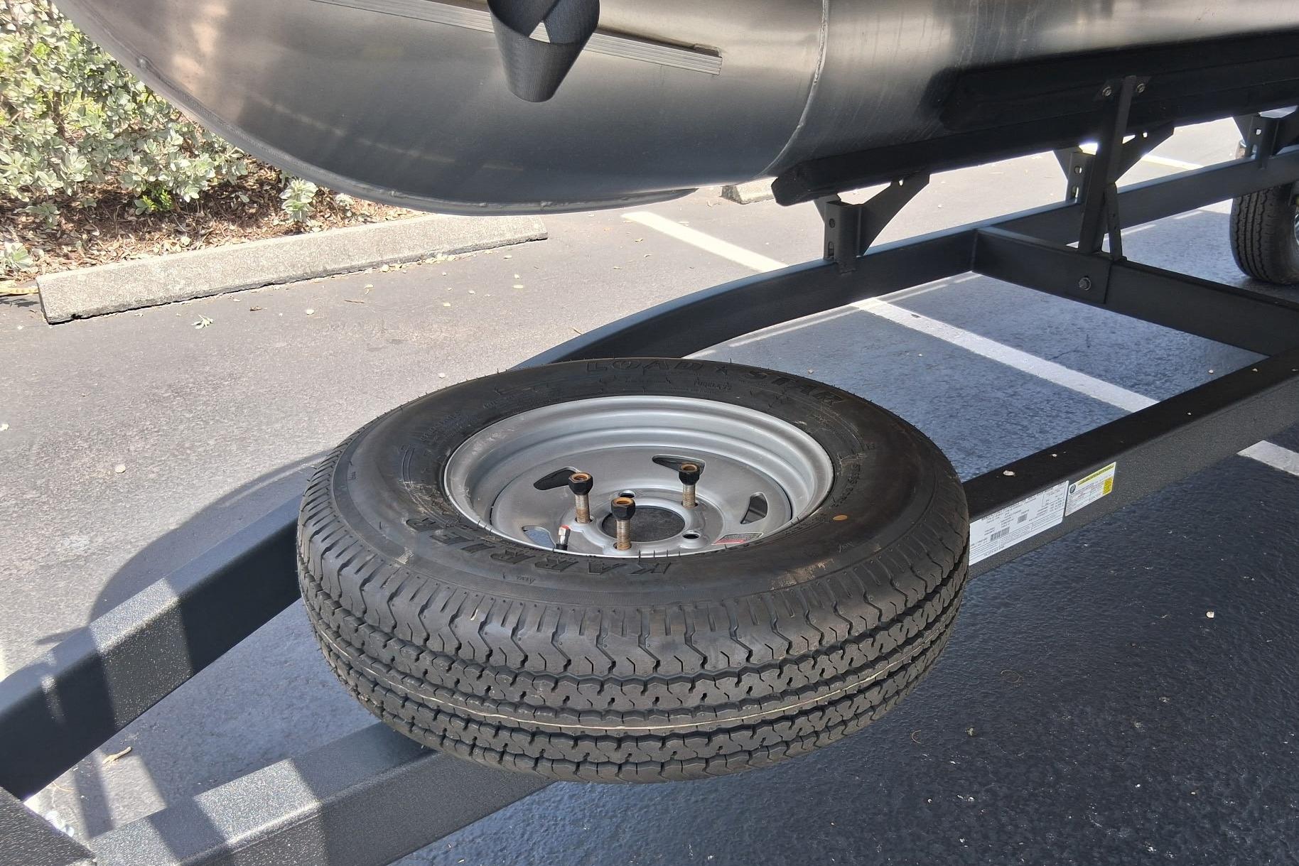 2026 Sun Tracker Bass Buggy 18 DLX trailer with spare tire in parking lot.