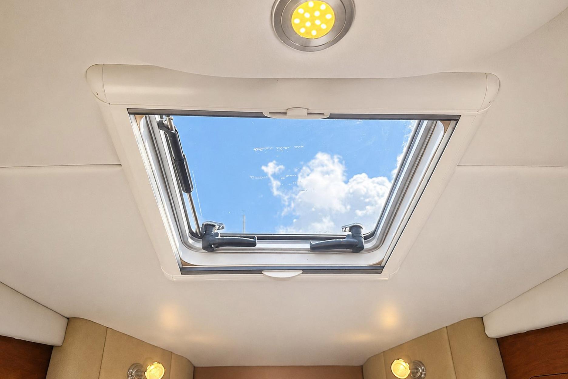 Interior view of 2012 Rinker 310 Express Cruiser LE skylight with blue sky and clouds.