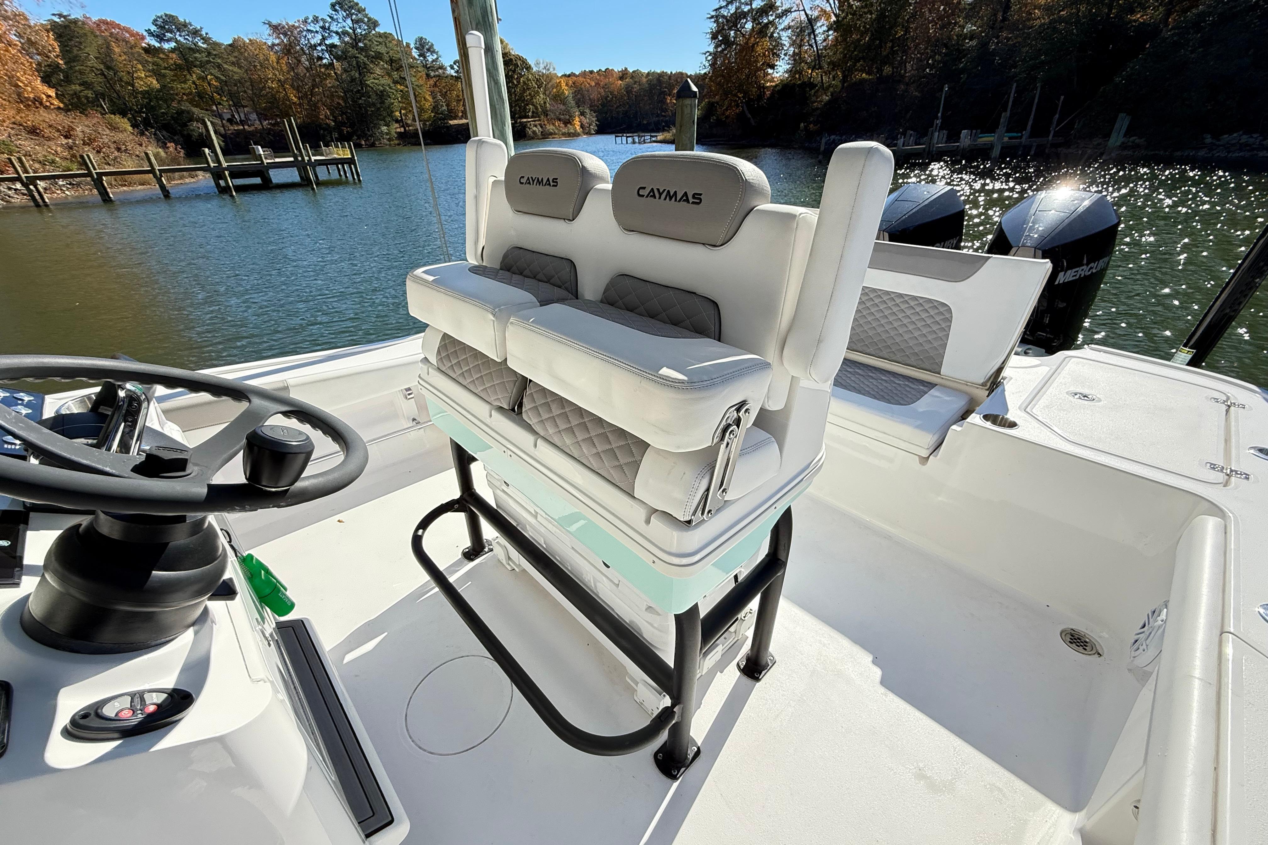 2023 Caymas 281 HB boat interior with helm and seating, docked by a scenic lake.