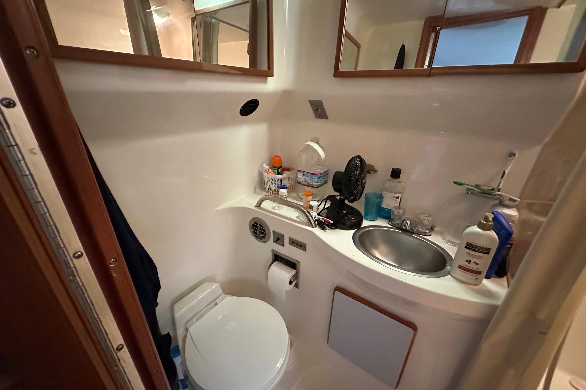 Compact bathroom in 1989 Sea Ray 380 Aft Cabin yacht, featuring sink and toilet.