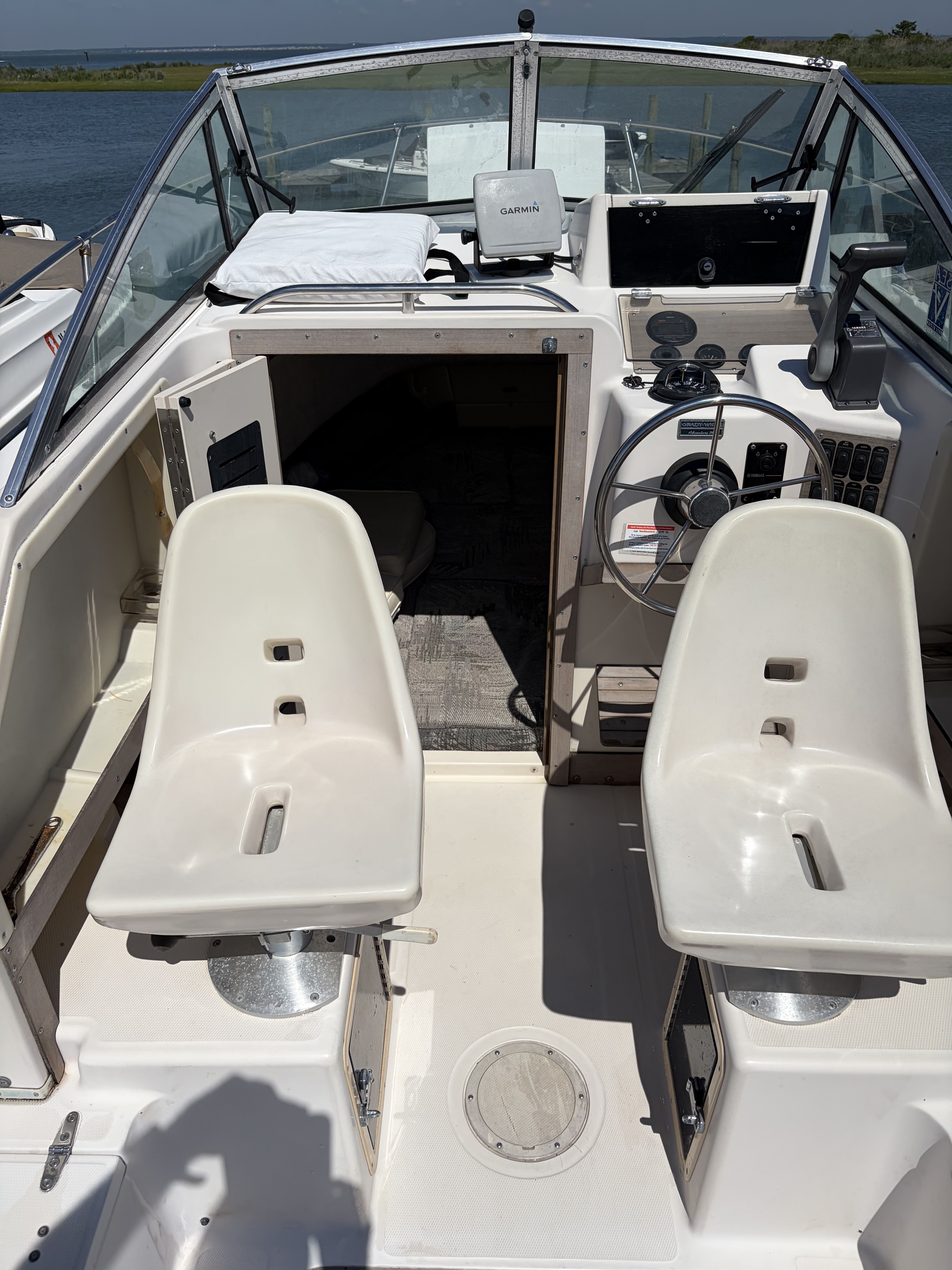 The image shows the cockpit of a Grady-White Adventure 208 boat with two white seats.