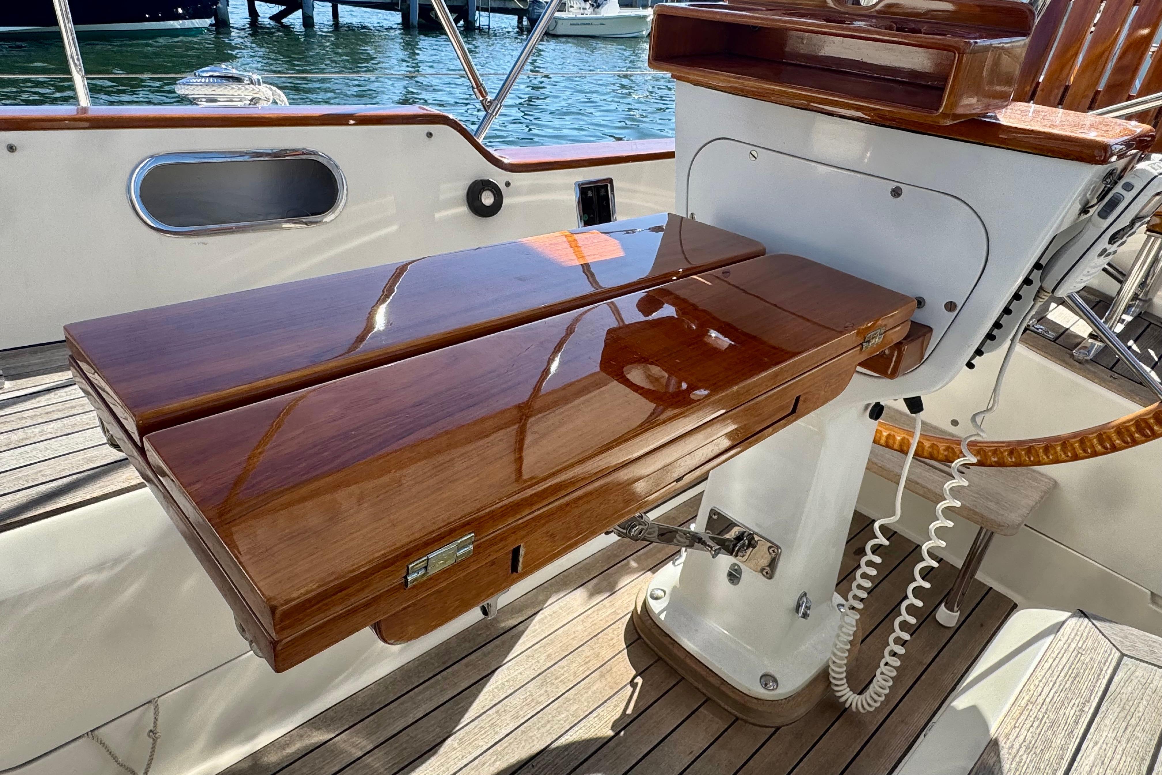 Polished wooden helm station on 1999 Hinckley Sou'wester 52 sailboat, docked by the water.