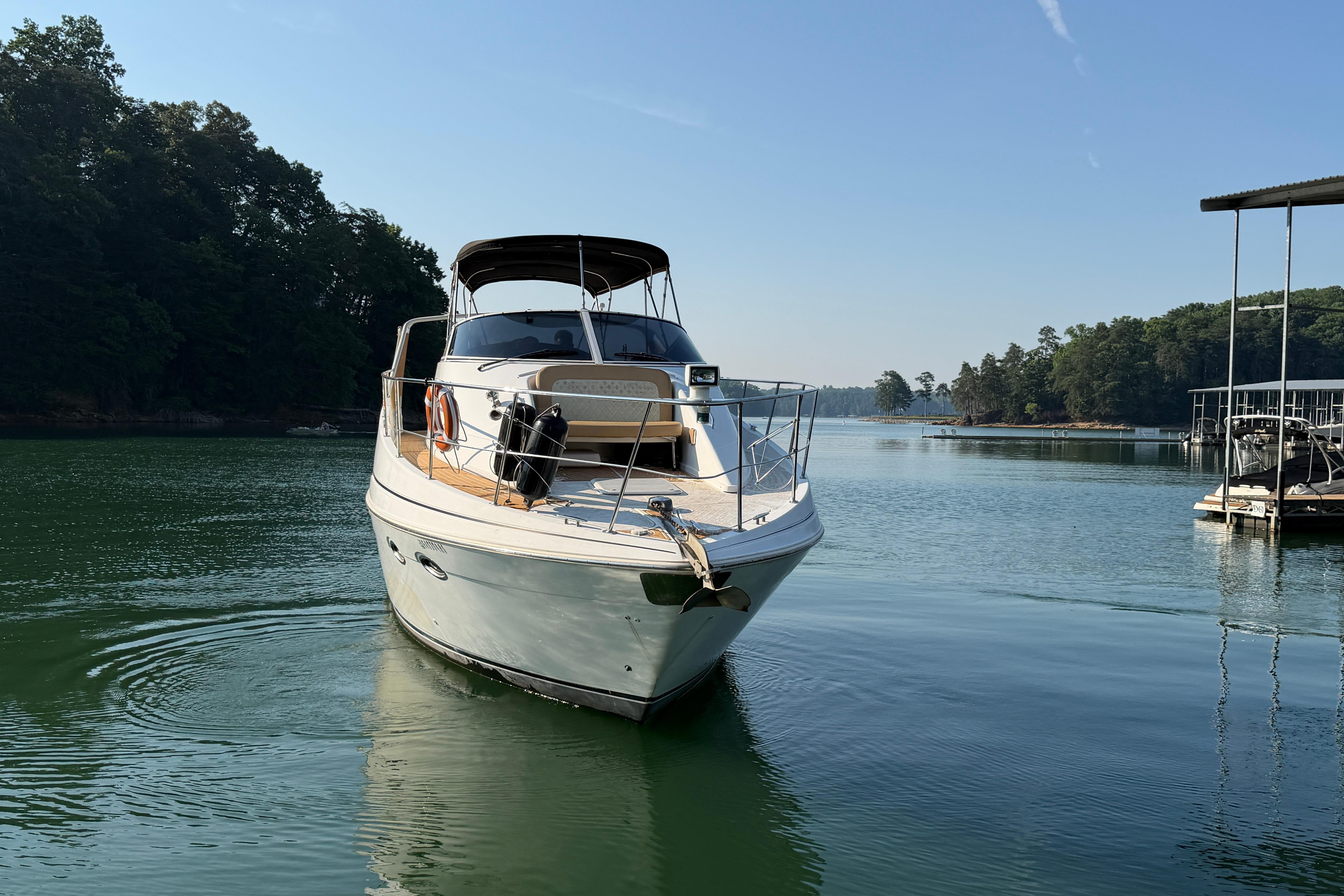 2003 Carver 350 Mariner yacht on serene lake with lush forest backdrop.