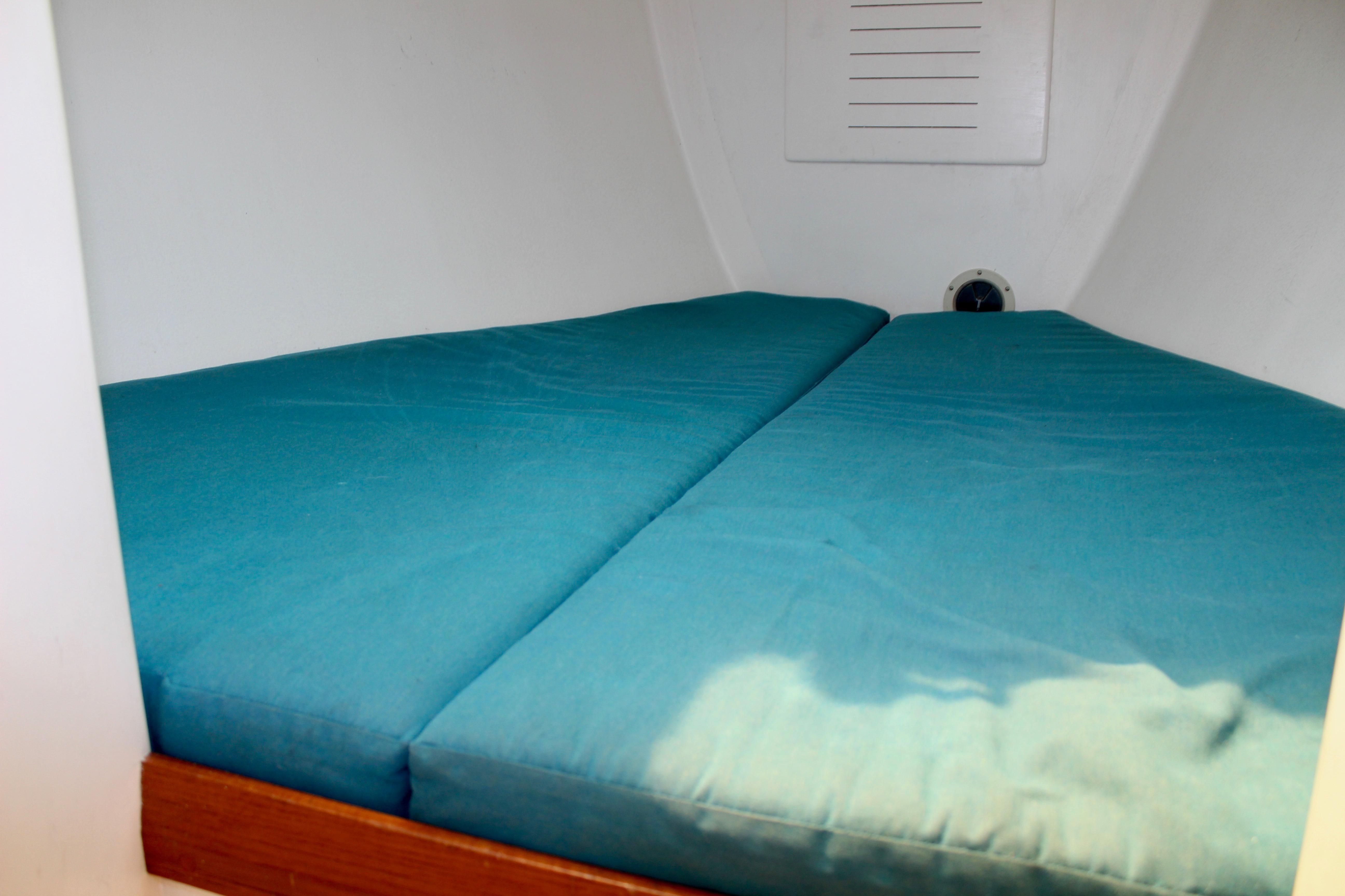 Cozy cabin bed with teal cushions in a 1993 Freya 39 sailboat.