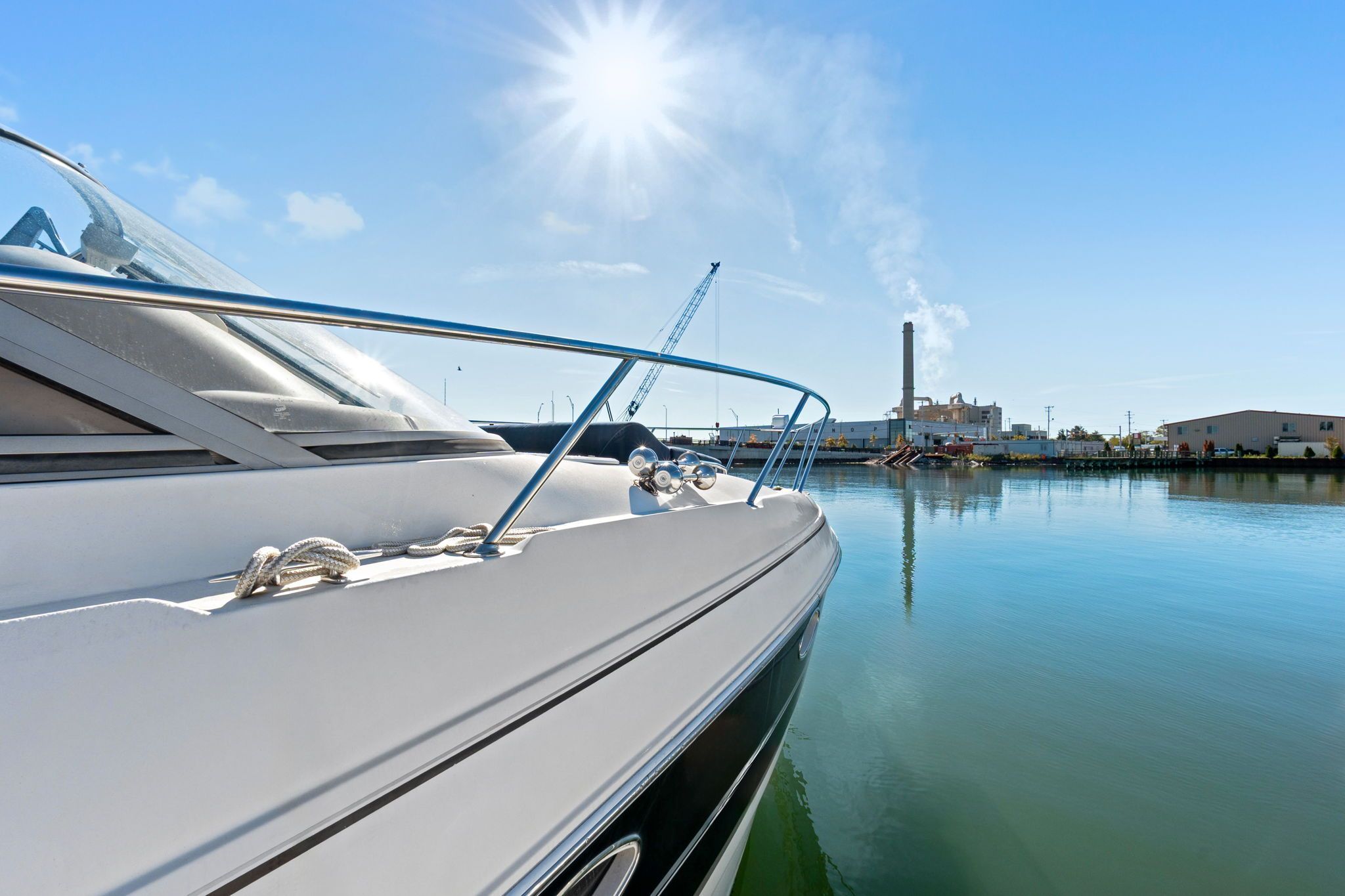 2007 Larson Cabrio 330 docked in a harbor, with clear skies and industrial buildings in the background.
