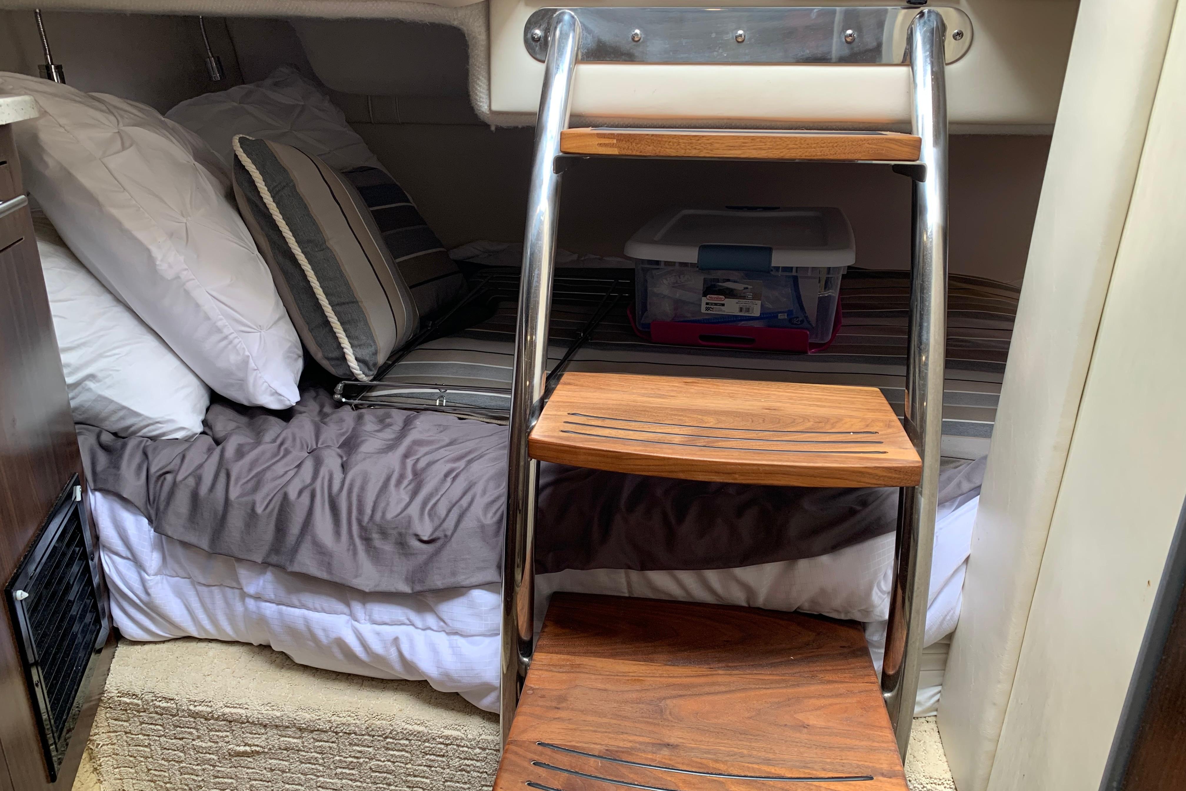 Cozy cabin interior of 2017 Regal 26 Express boat with wooden steps and bedding.