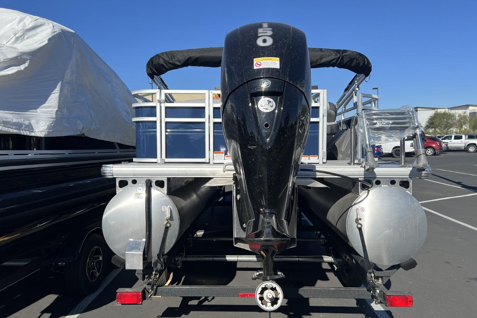 2026 Sun Tracker SportFish 22 DLX pontoon boat with powerful outboard motor in parking lot.