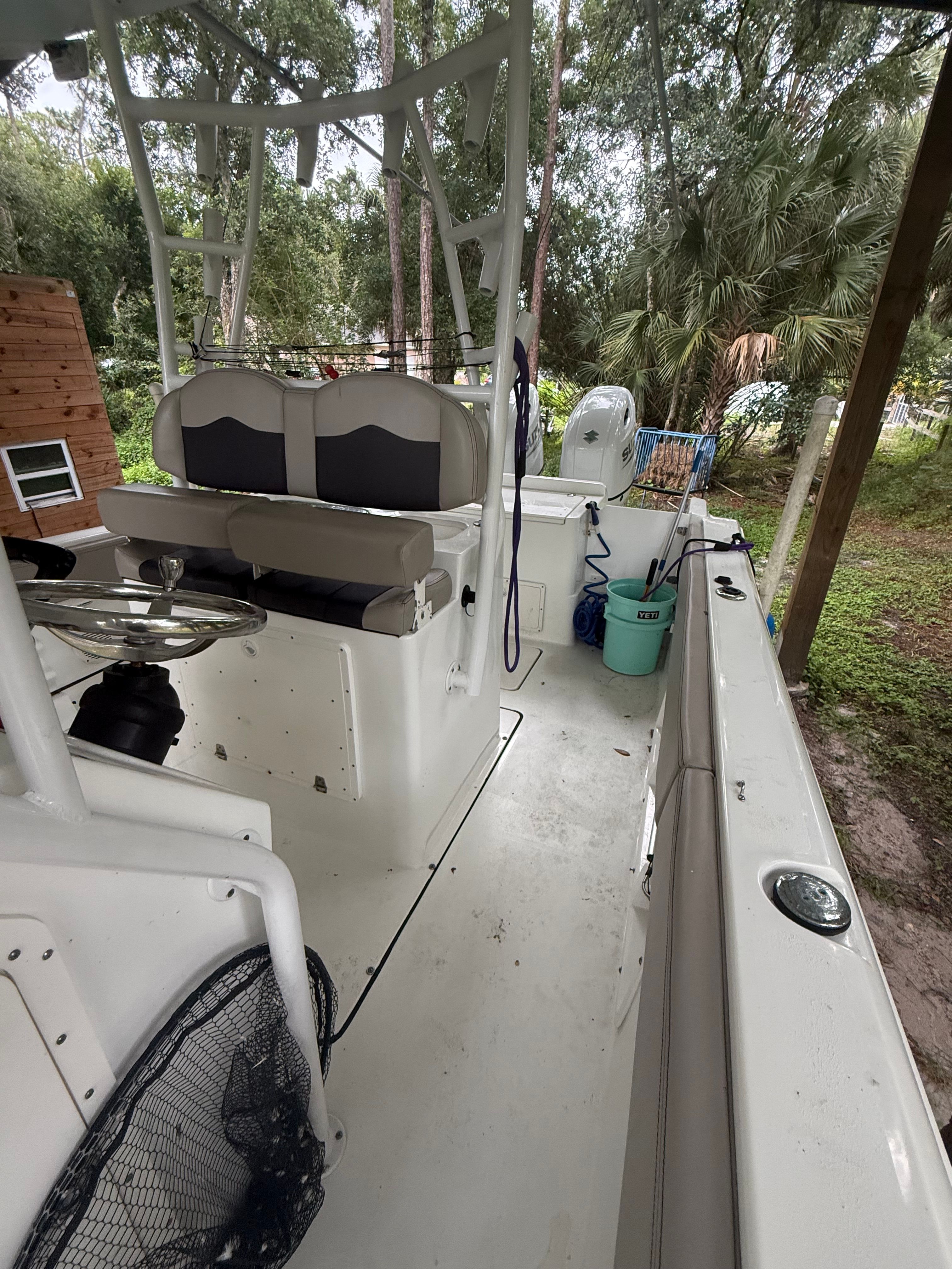 A 2021 Clearwater 2508 Center Console boat is outdoors, surrounded by trees.