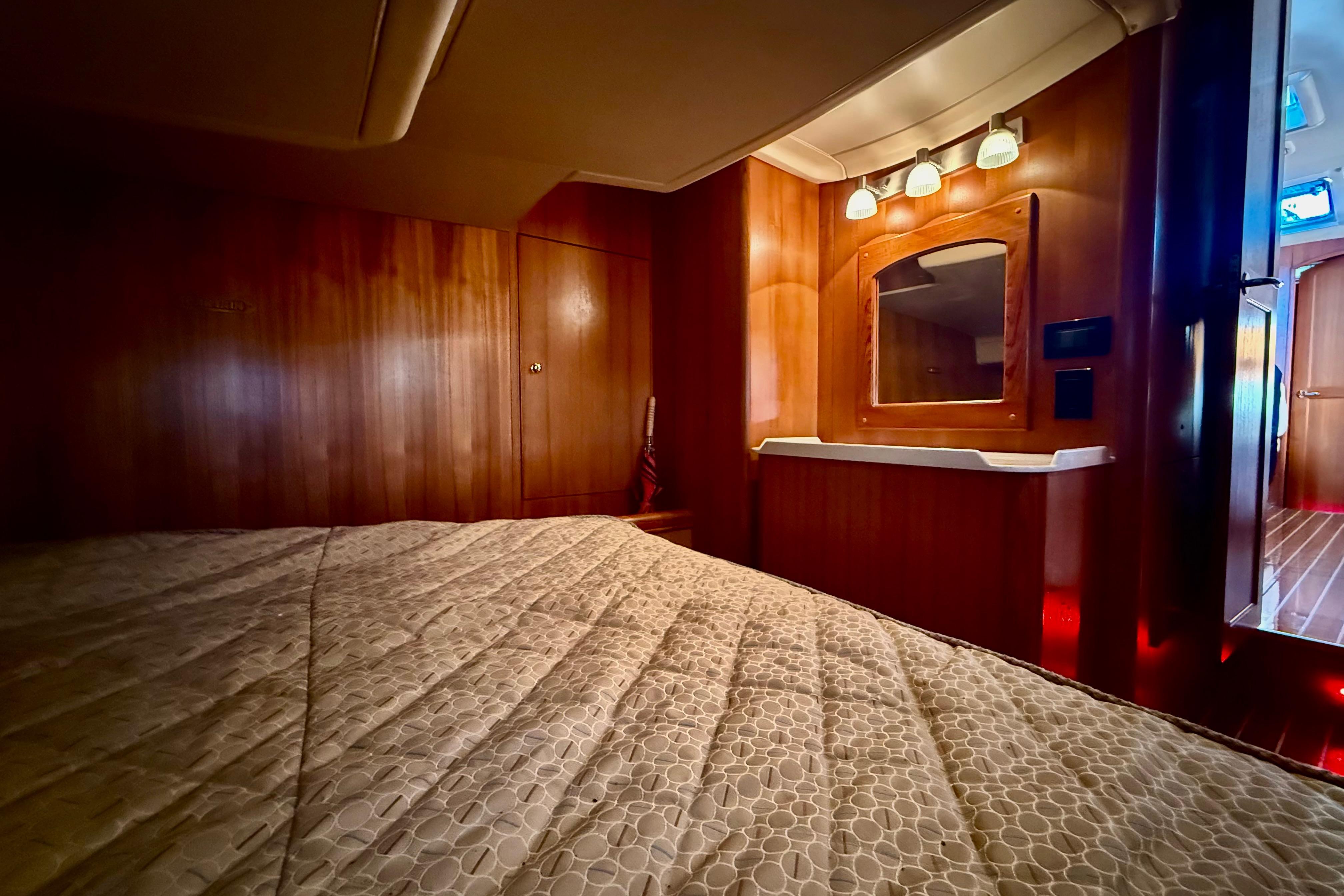 Luxurious interior of 2007 Hunter 41 Deck Salon yacht with wood paneling and cozy bedding.