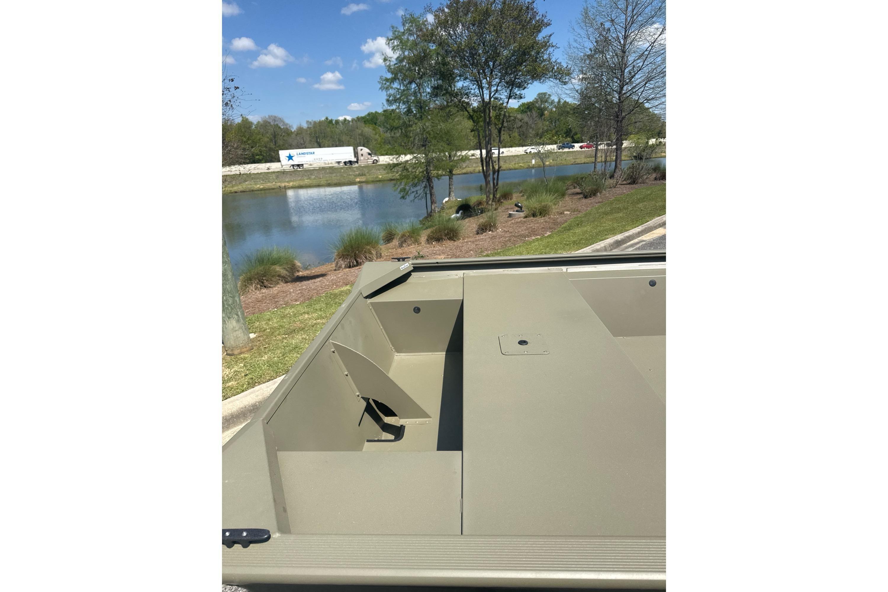 2026 Tracker Grizzly 1754 Utility boat near a scenic pond with trees and blue sky.