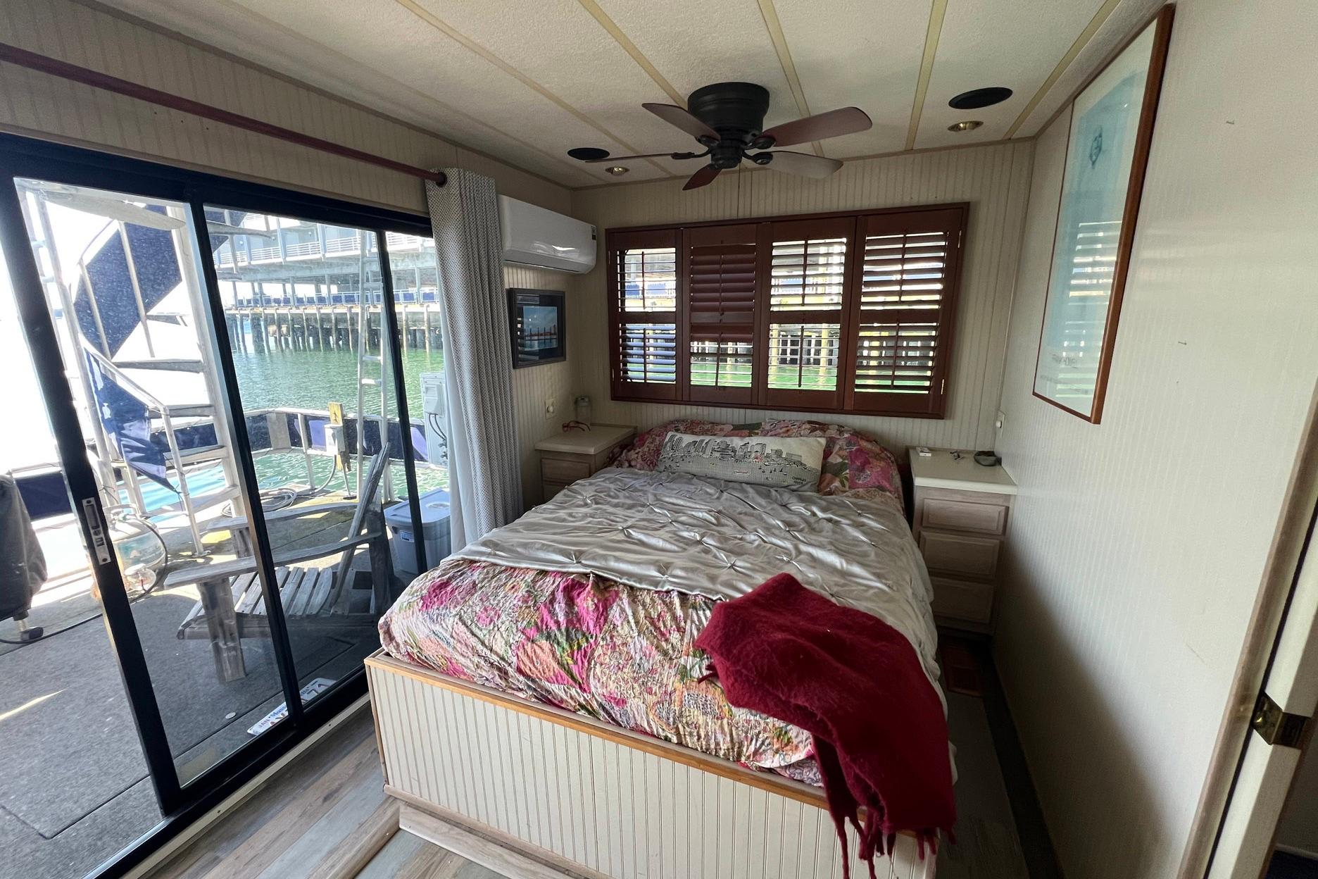 Cozy bedroom in a 1993 Sumerset houseboat with waterfront view and sliding glass doors.