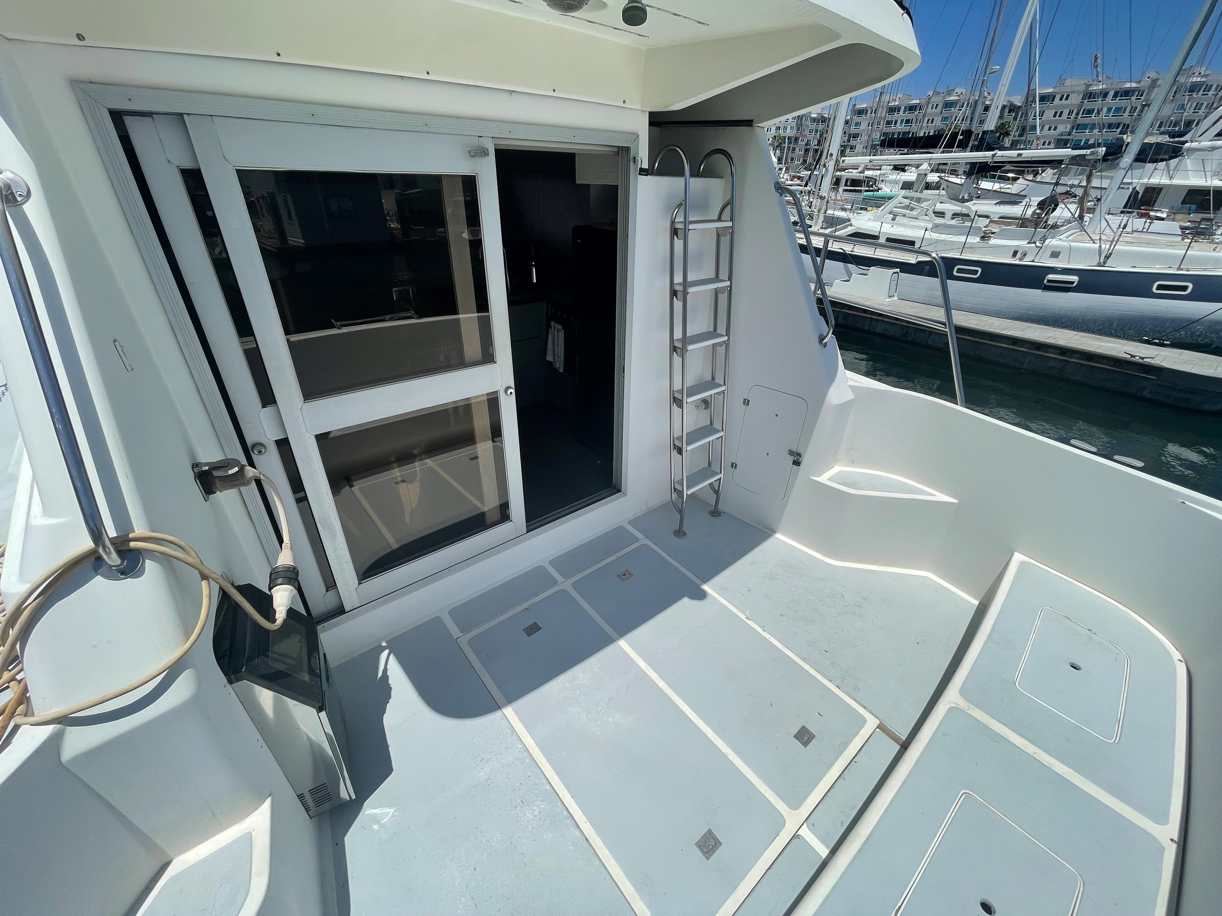 1986 Sea Hawk Sedan boat deck with sliding door and ladder, docked at marina.