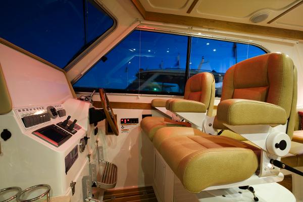 2026 Back Cove 372 boat interior with helm station and two cushioned seats.
