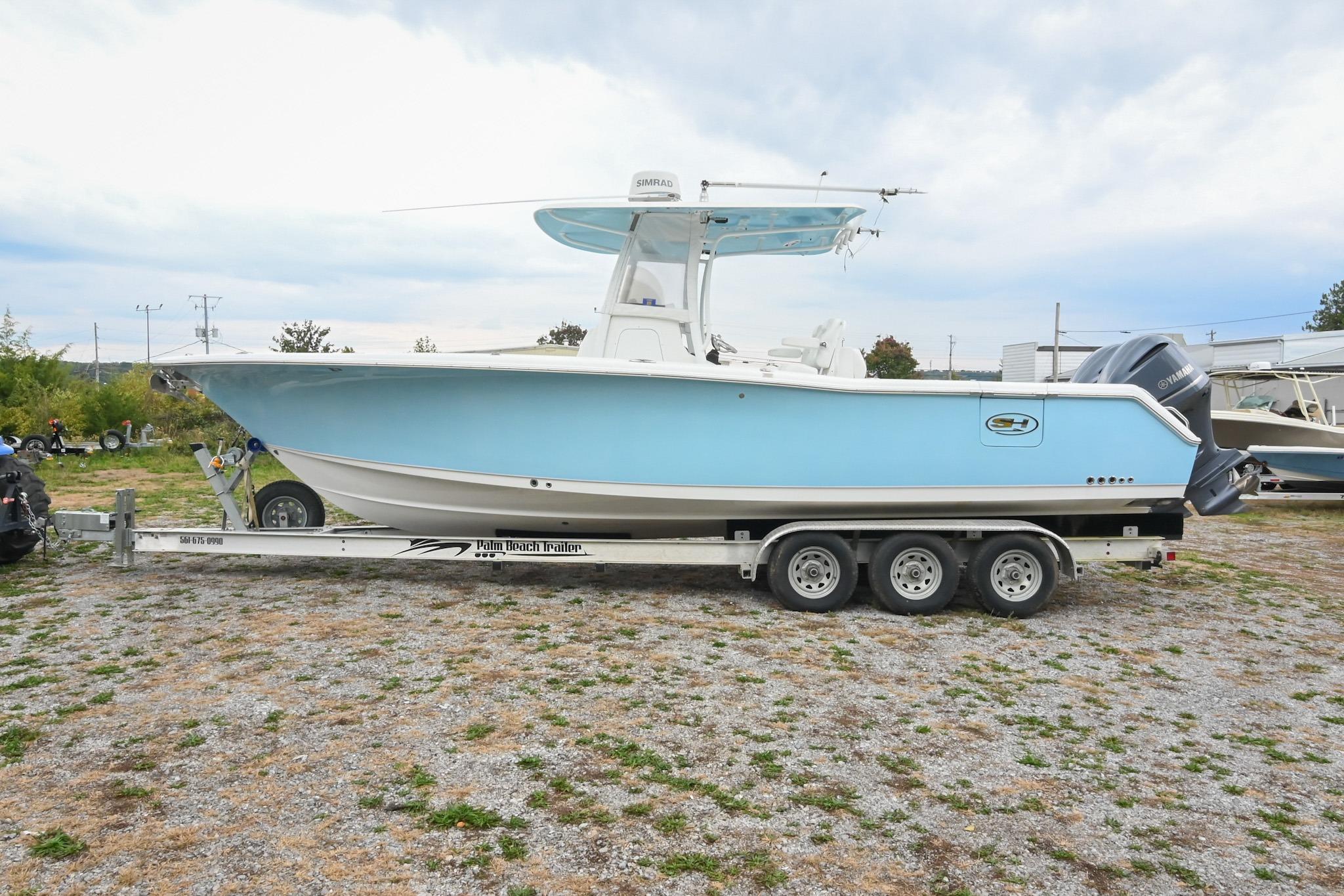 2015 Sea Hunt Gamefish 30 boat on trailer, light blue hull, parked outdoors.