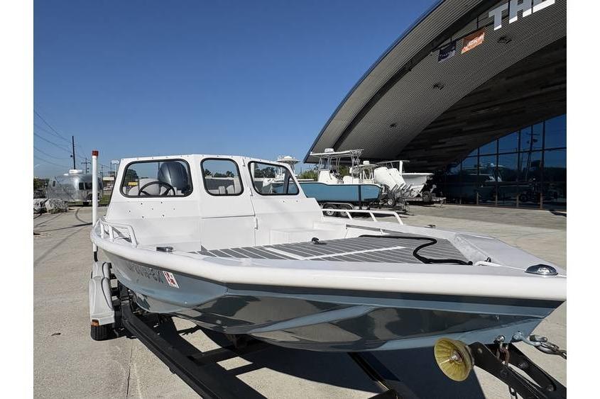 1997 Scully's 18 WT boat on trailer outside a modern building under clear blue sky.