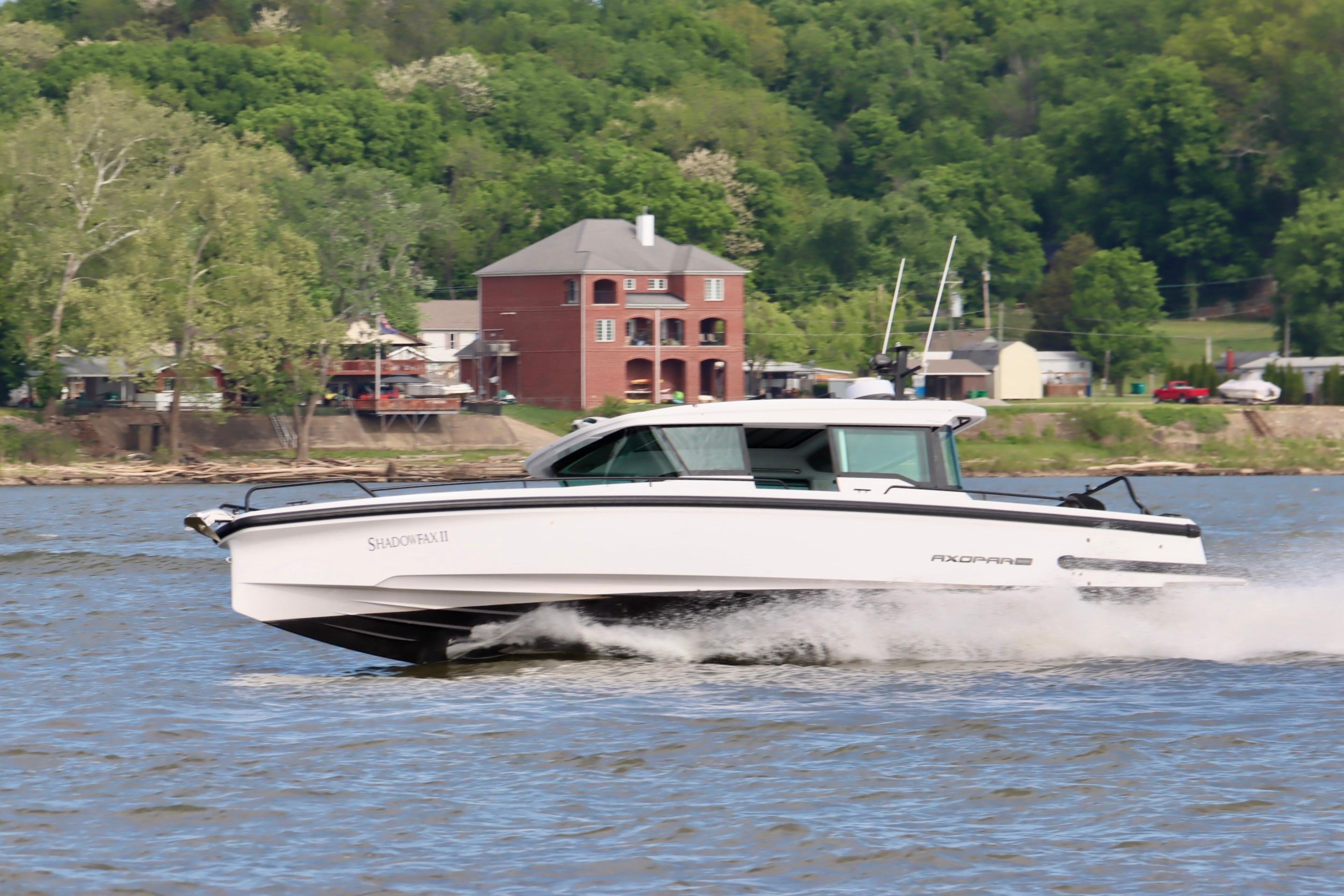 2022 Axopar 37 XC Cross Cabin cruising on a river with lush green background.