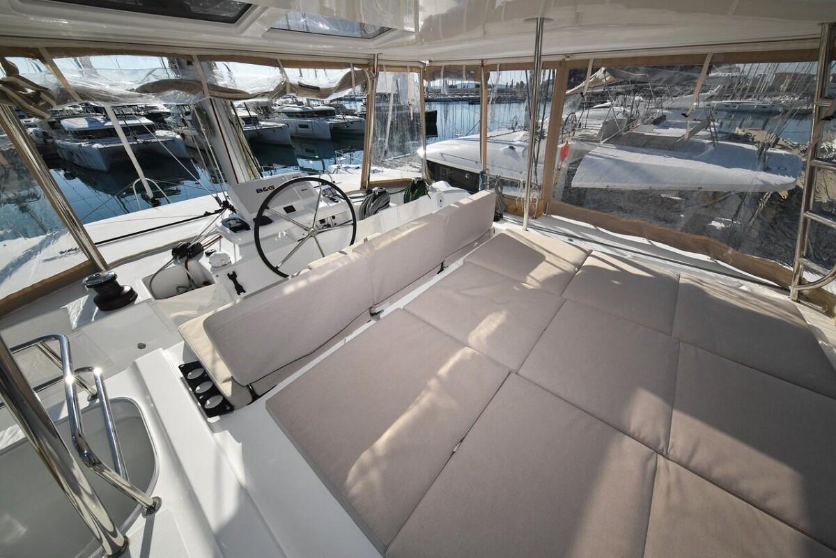 Lagoon 50 catamaran 2021 model, spacious cockpit with cushioned seating, docked at marina.