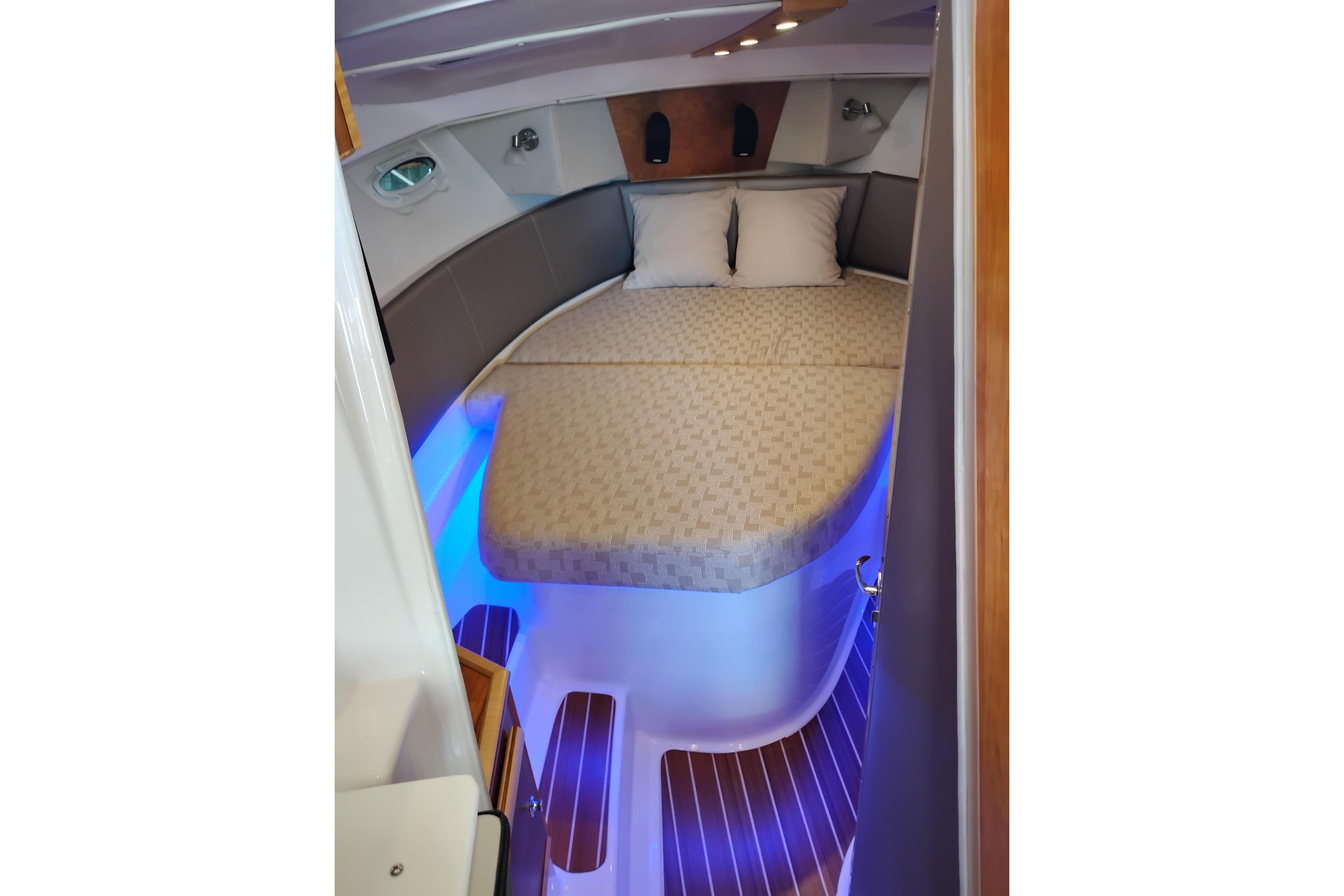 Interior cabin of 2022 Cutwater C-32 Coupe with cozy bed and ambient lighting.