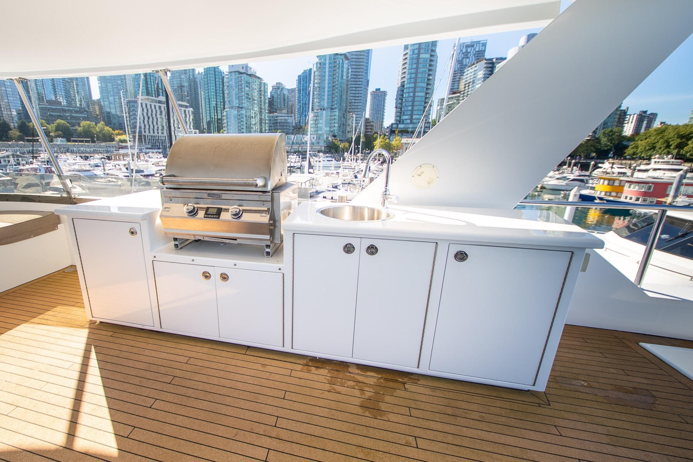 Outdoor yacht kitchen with grill and sink, Crescent Custom 1992, overlooking marina and city skyline.