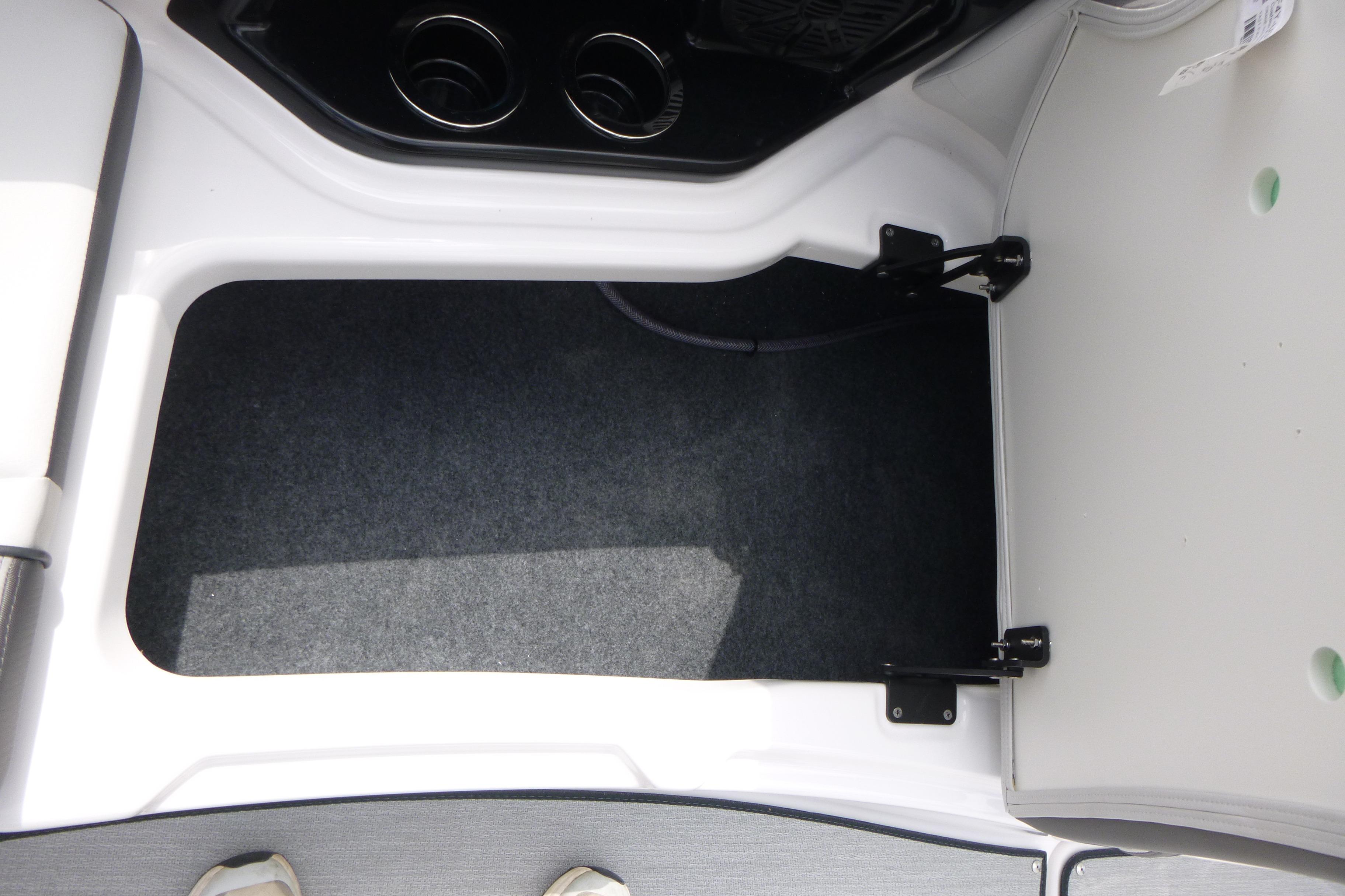 2026 Yamaha AR250 boat storage compartment with cup holders and carpeted interior.