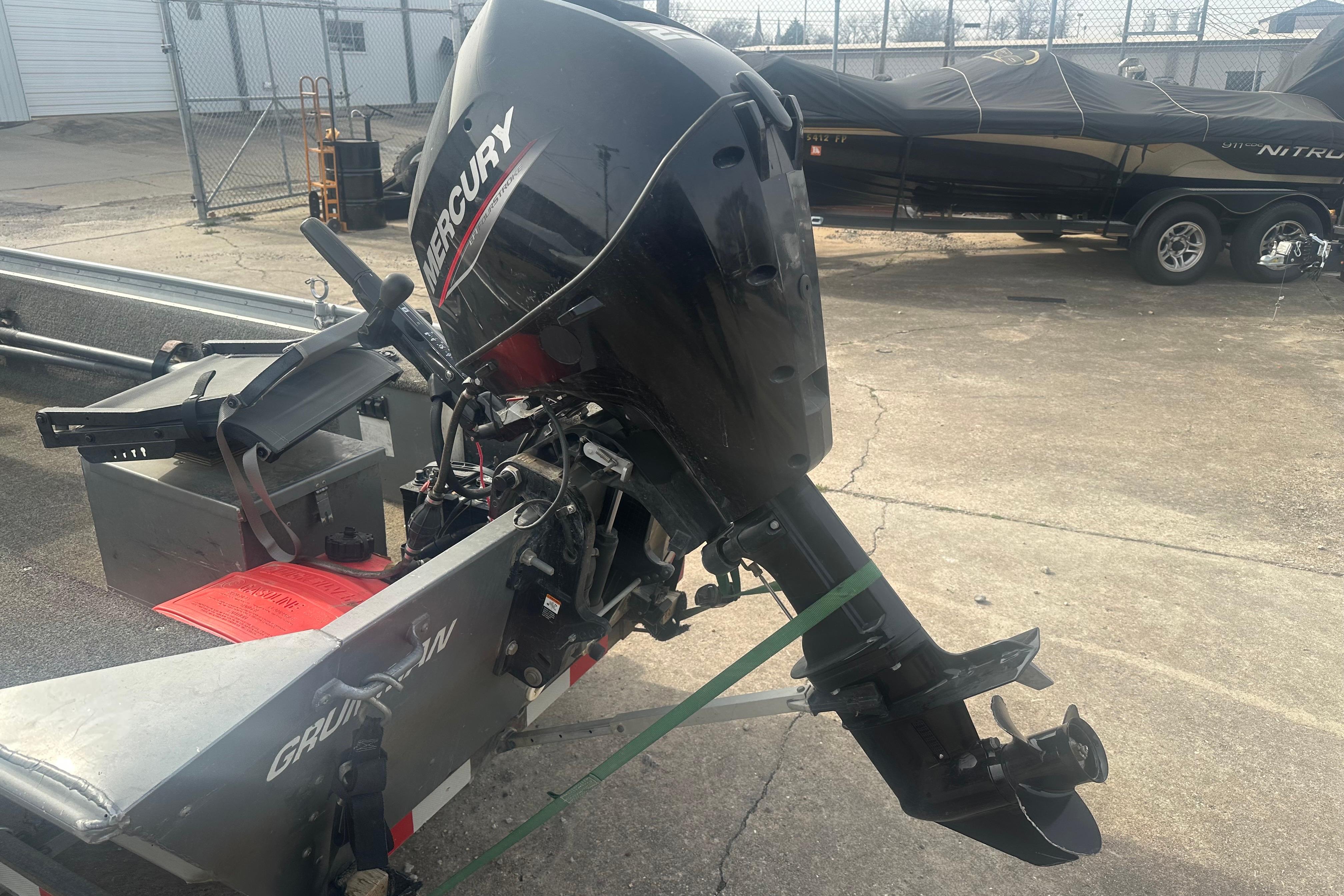 1991 Grumman Rogue 150 T boat with Mercury outboard motor in a parking lot.