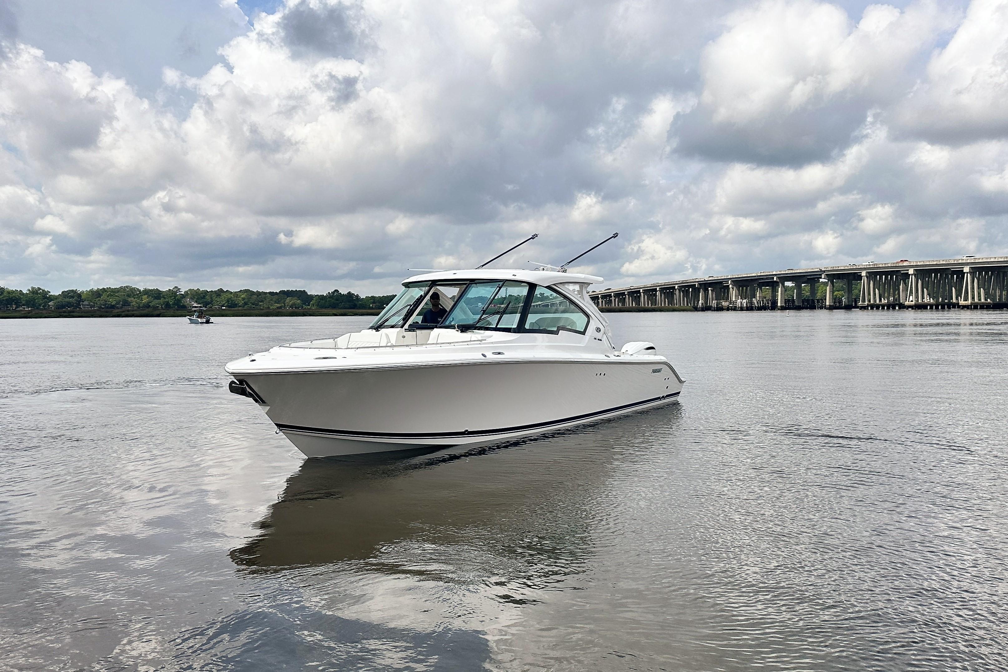 2025 Pursuit DC 326 Dual Console boat on calm water under cloudy sky.