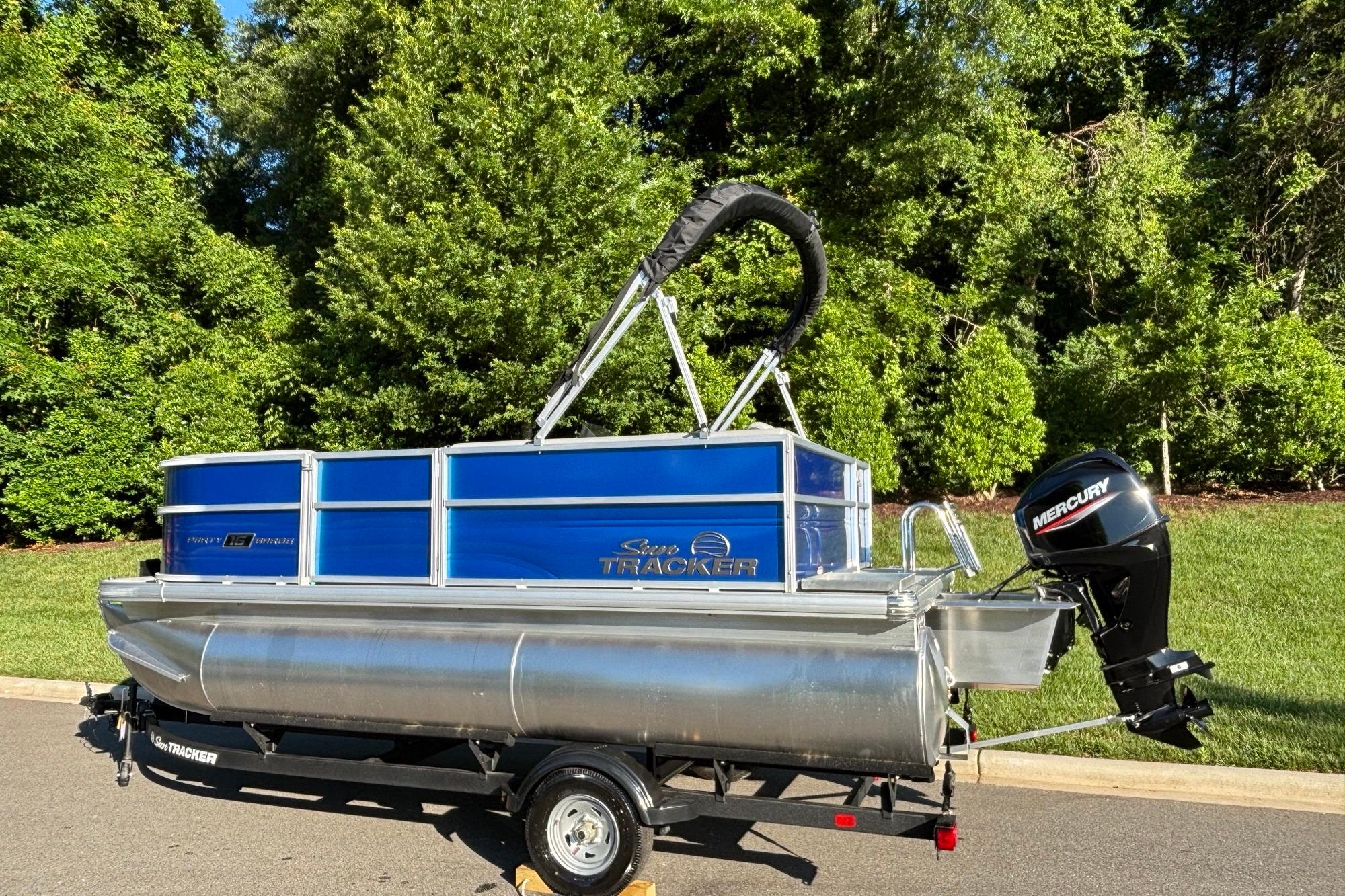 2026 Sun Tracker Party Barge 16 DLX pontoon boat on trailer, parked outdoors.