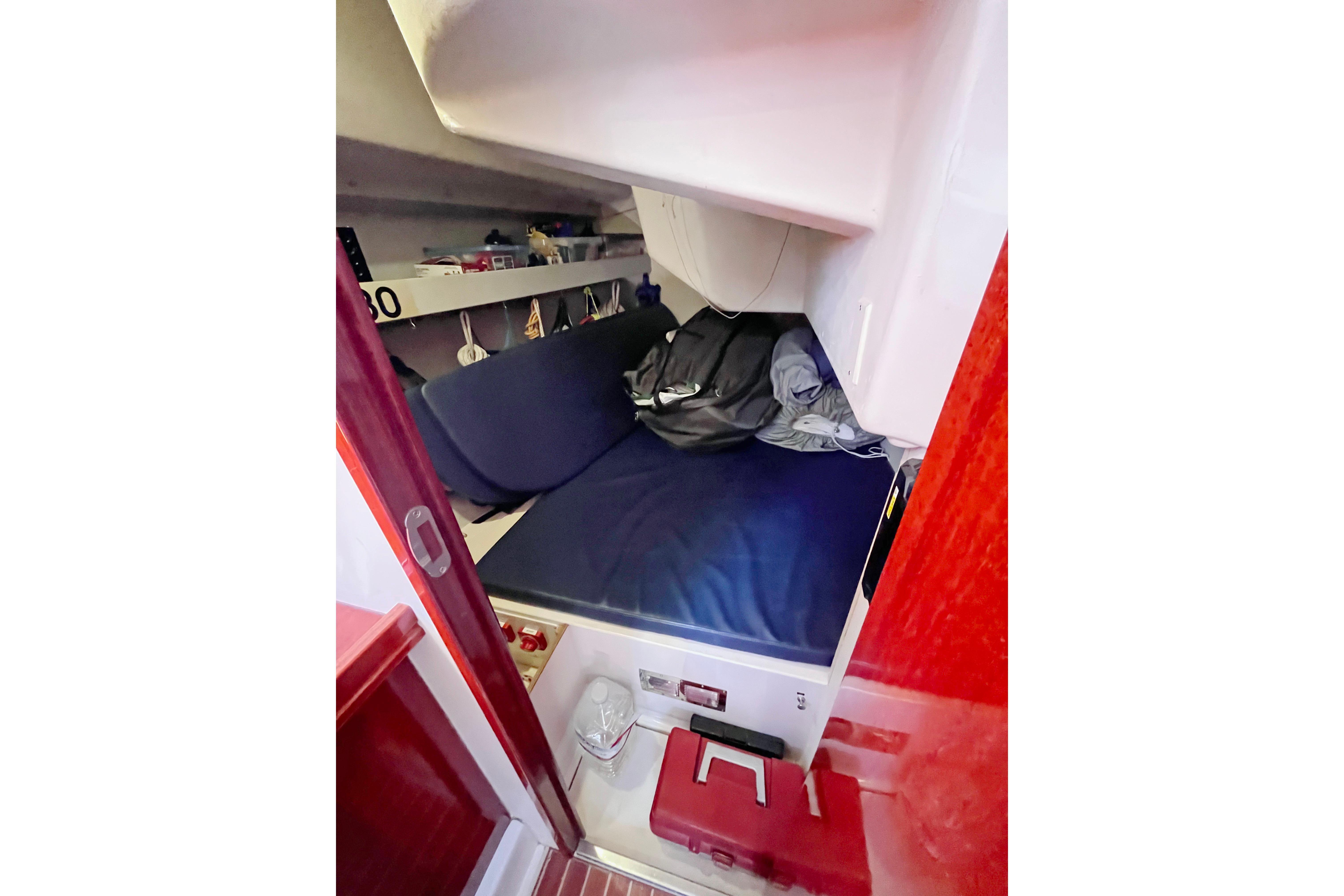 Cozy cabin interior of 2004 Hanse 411 sailboat with blue bedding and storage shelves.