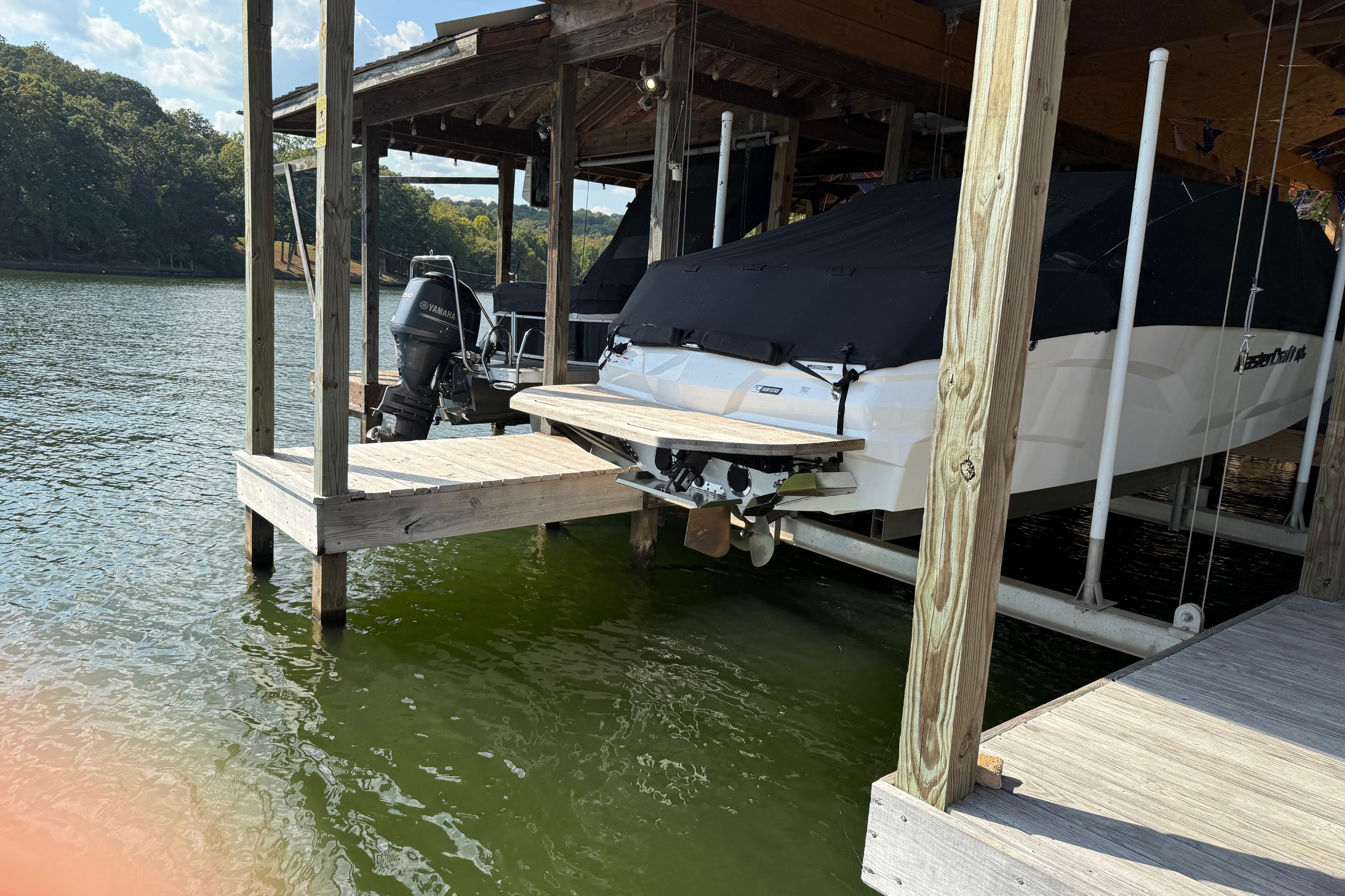 2022 MasterCraft NXT24 boat docked with cover on a serene lake.