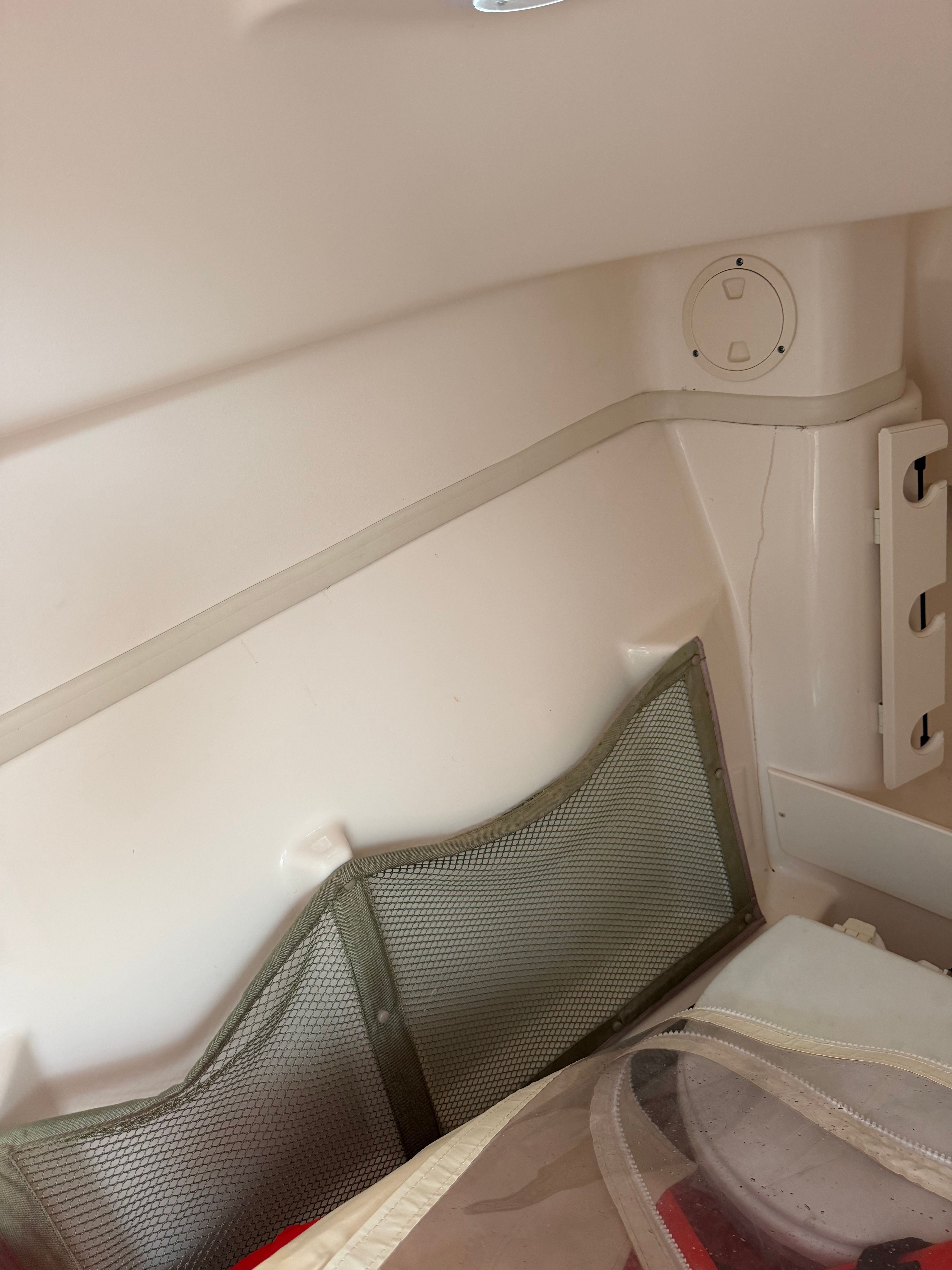 Interior of a boat with a storage net and plastic paneling.