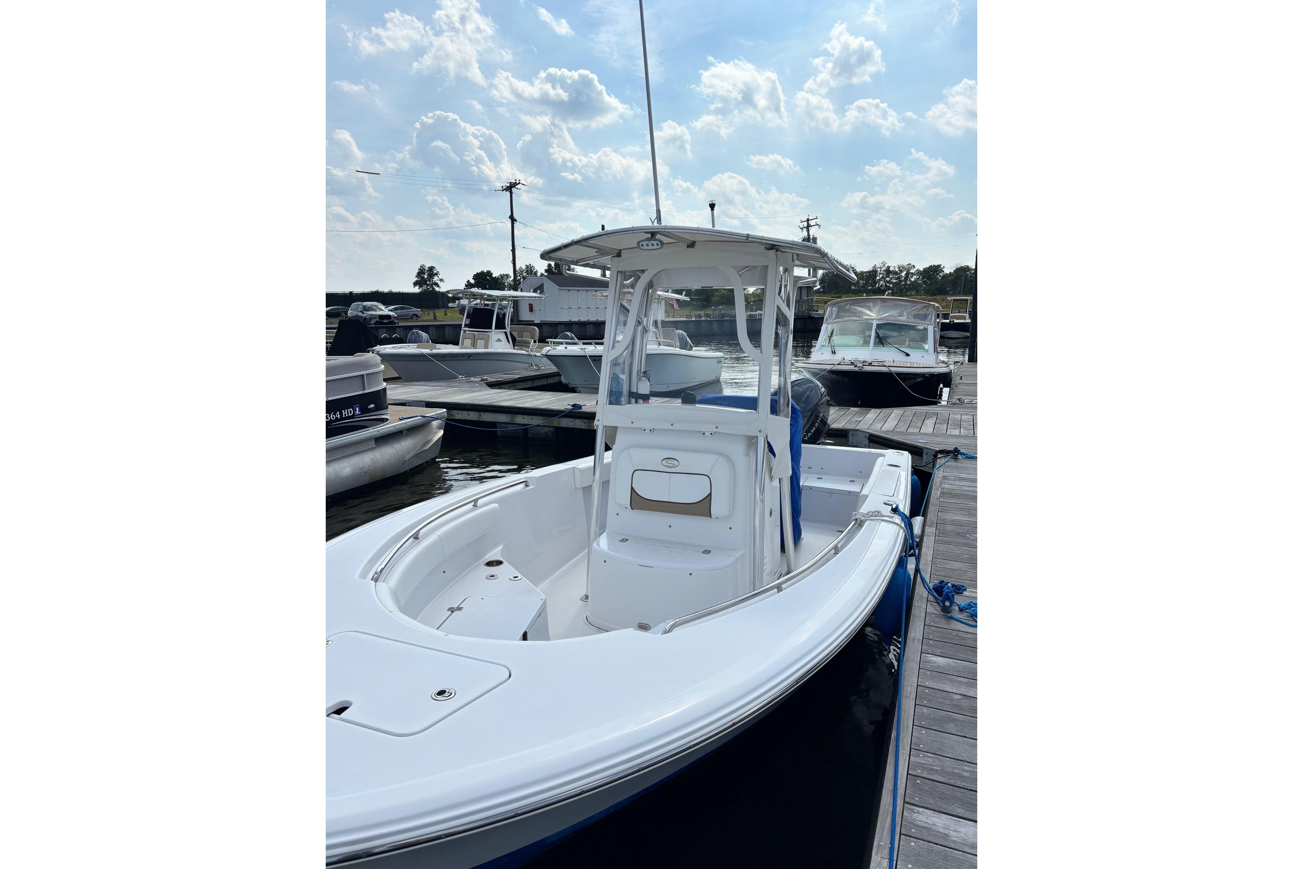 2014 Sportsman Heritage 211 Center Console boat docked at marina under cloudy sky.