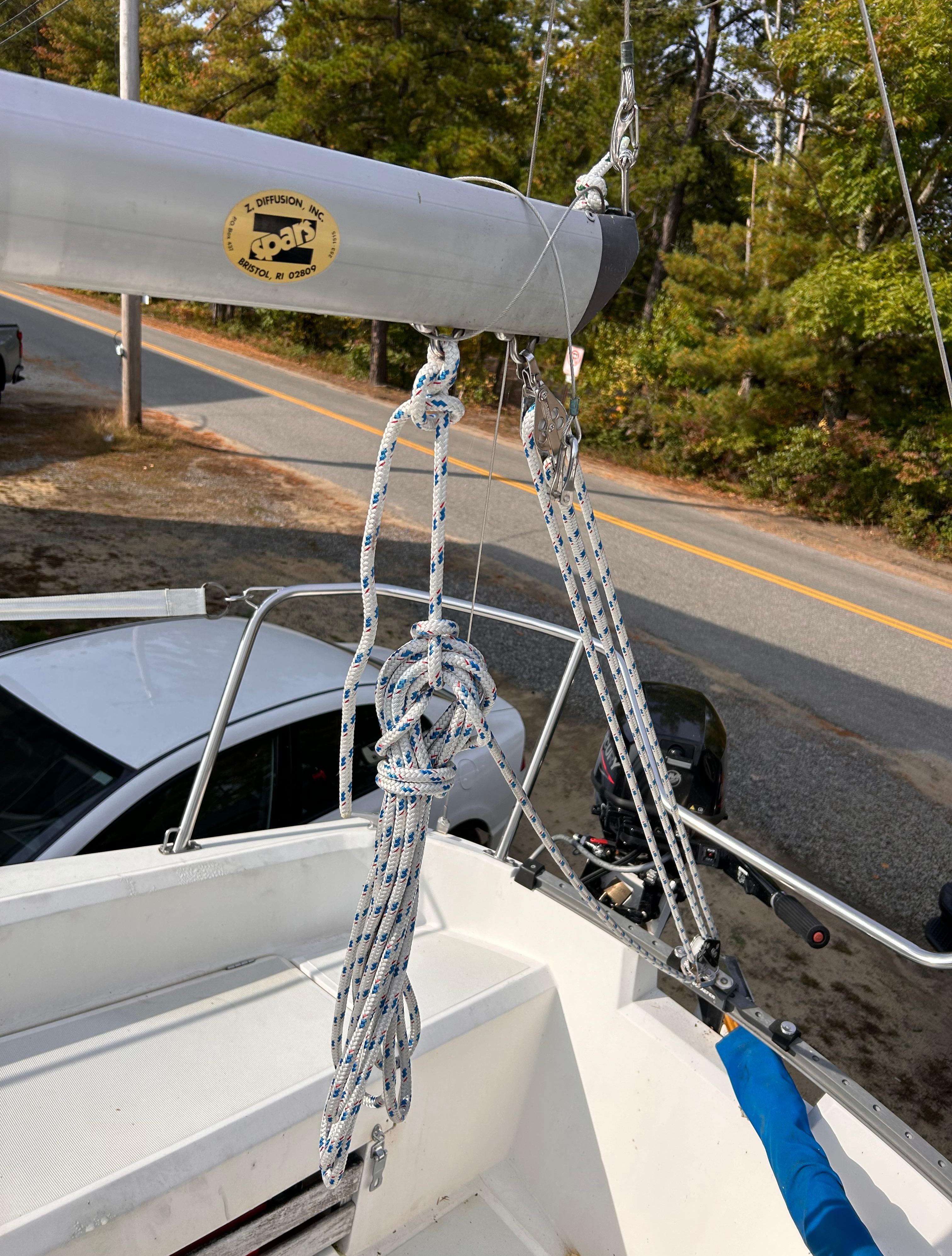 Sailboat rigging on a 1986 CAL 22, parked near a road with trees.