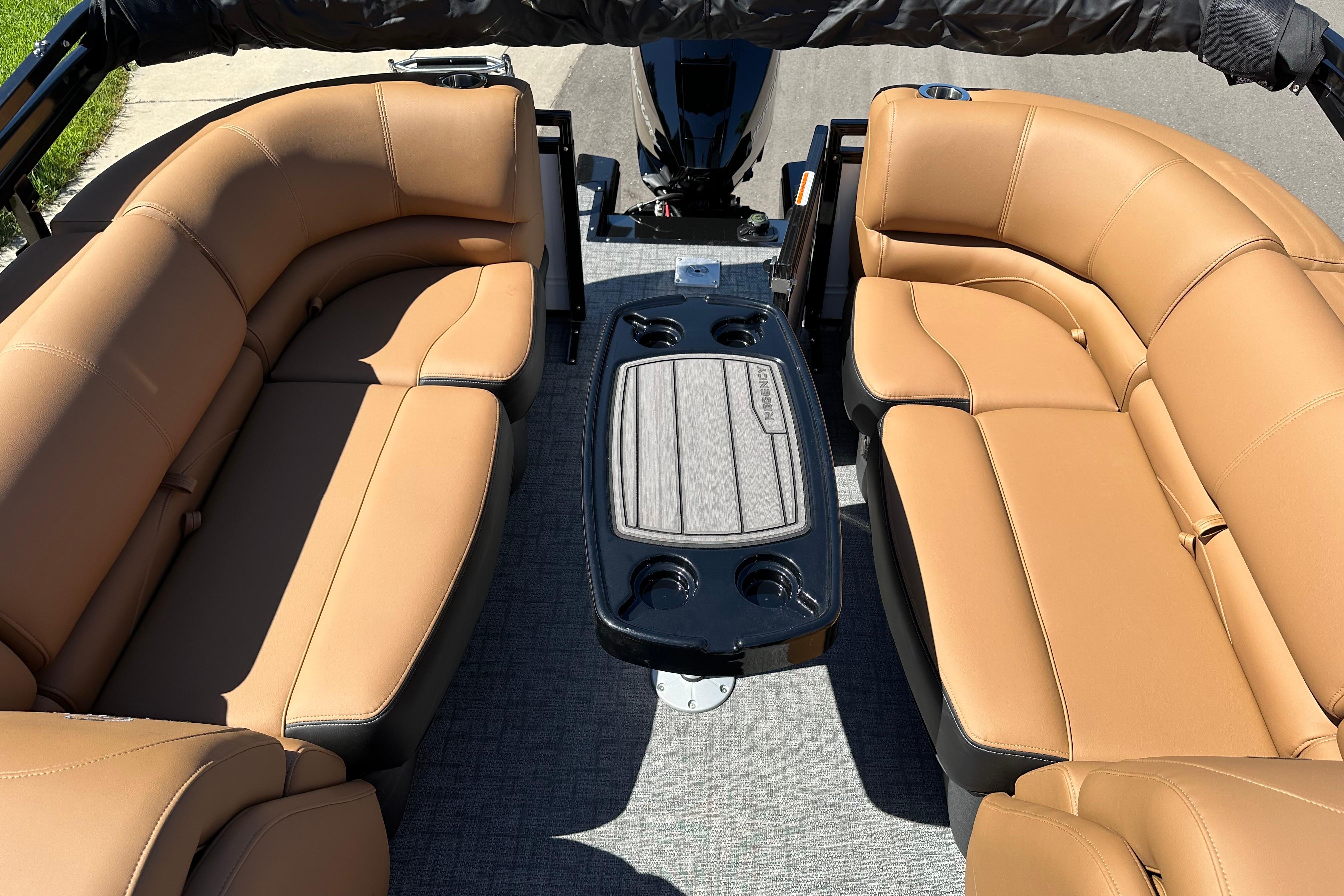 Luxurious seating on 2026 Regency 230 DL boat with tan leather upholstery and central table.