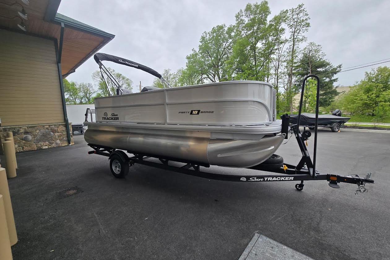 2026 Sun Tracker Party Barge 18 DLX pontoon boat on trailer, parked outdoors.