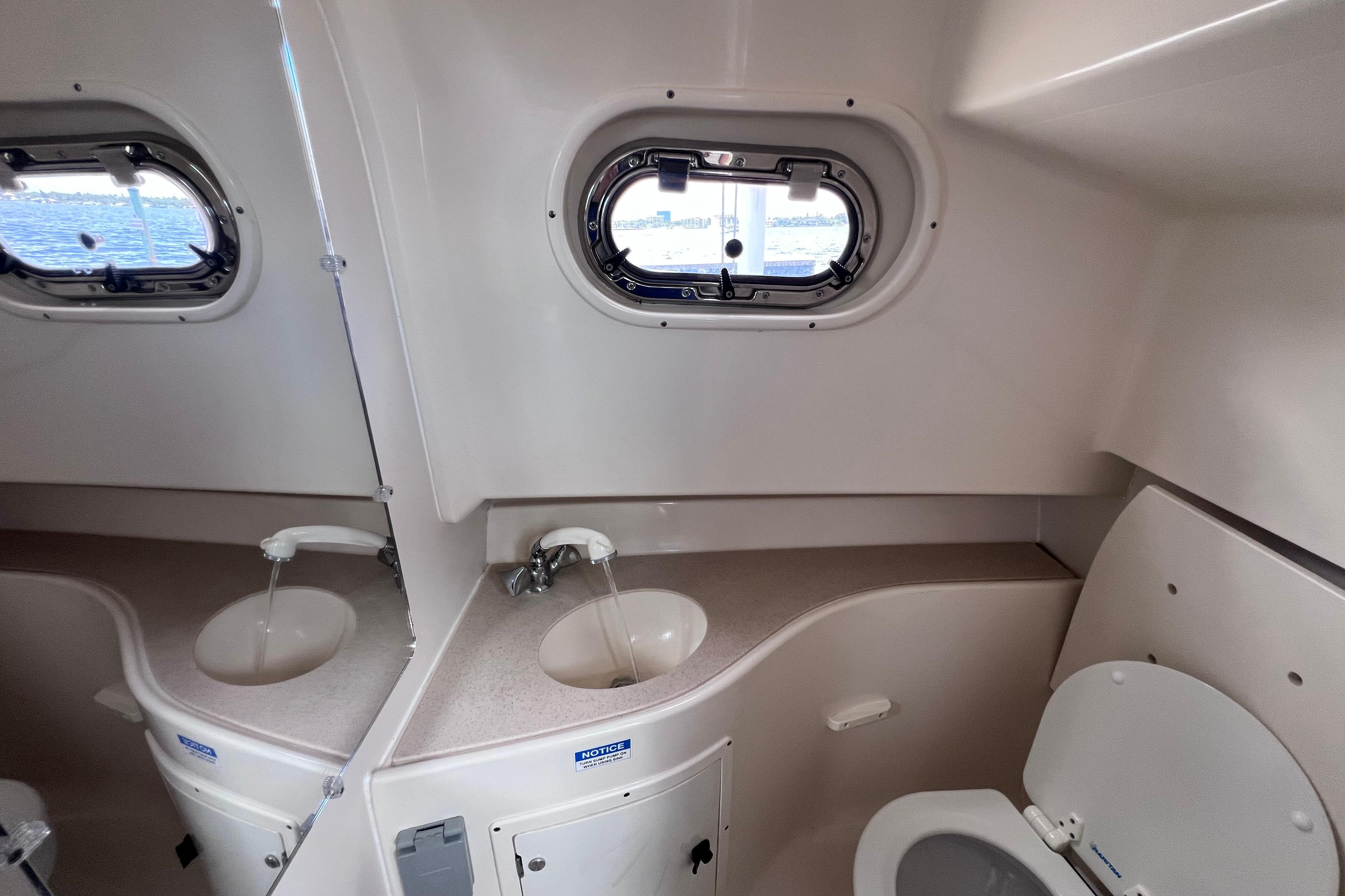 2004 Pursuit 2870 Walkaround boat bathroom with sink, toilet, and porthole window.