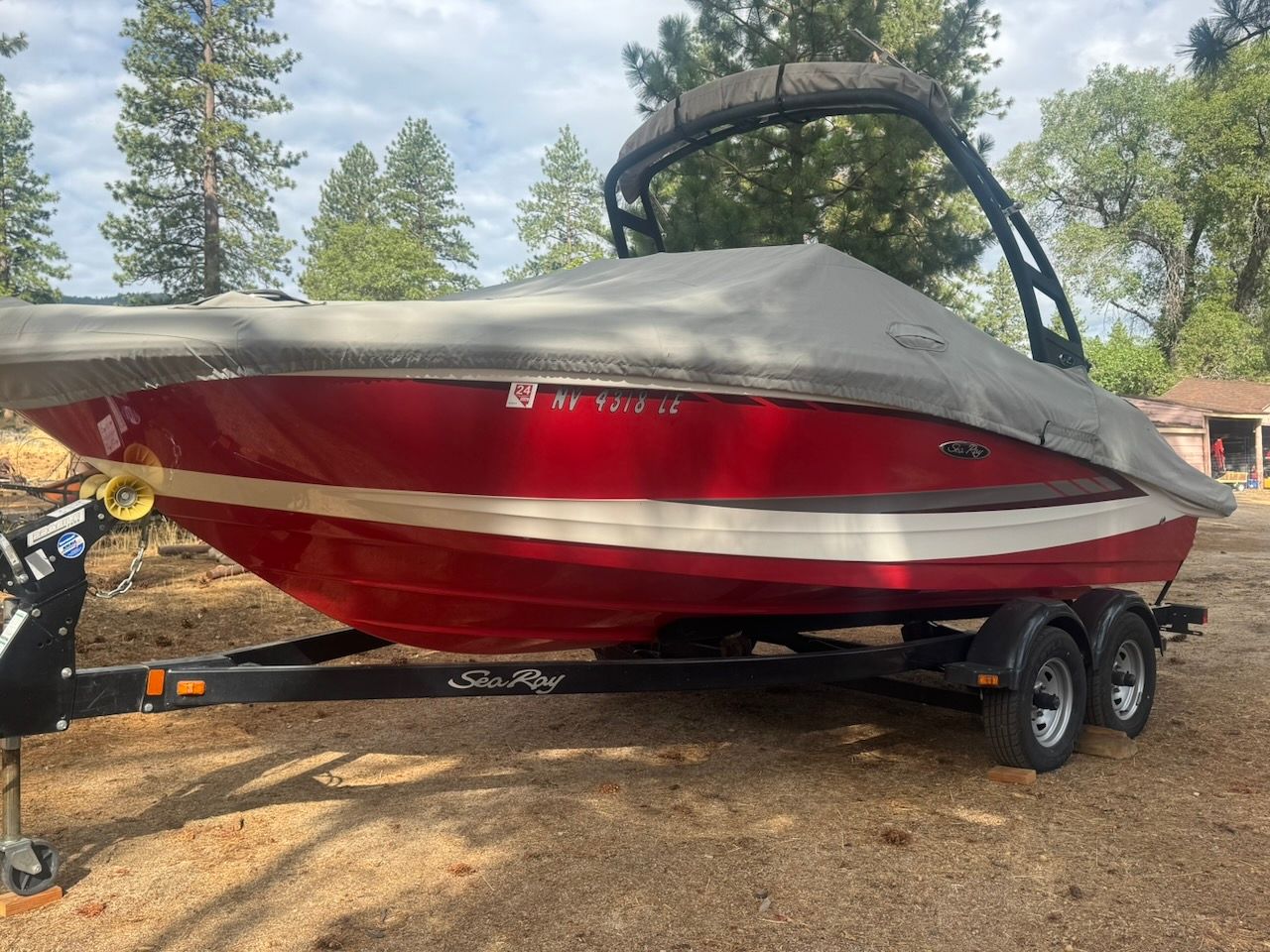 A red 2016 Sea Ray SPX 190 Outboard boat on a trailer, covered with a tarp.