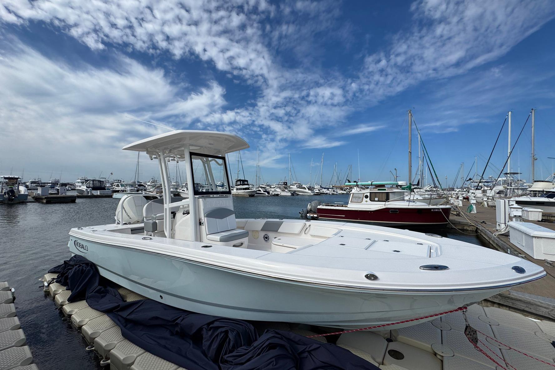 2021 Robalo 246 Cayman boat docked at marina under blue sky.