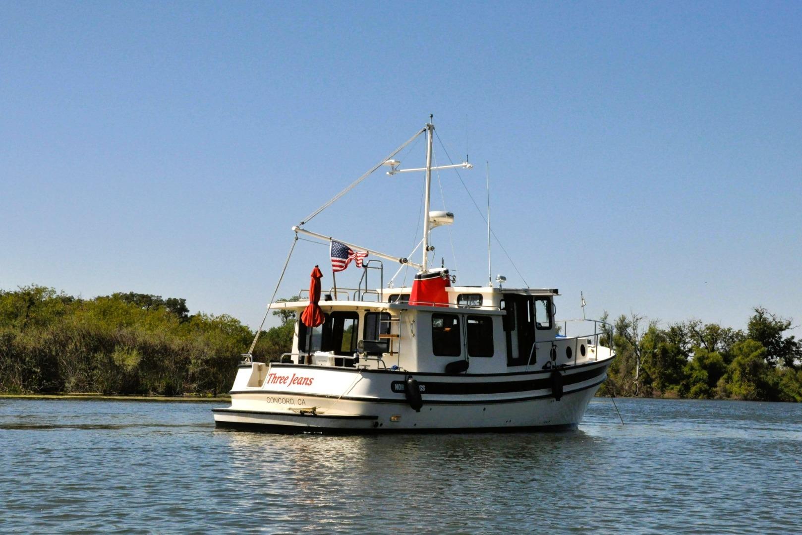 2002 Nordic Tug 37 boat on calm water with clear blue sky.