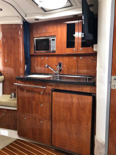 Galley of the 2008 Four Winns V338 with wood cabinets, sink, microwave, and refrigerator.