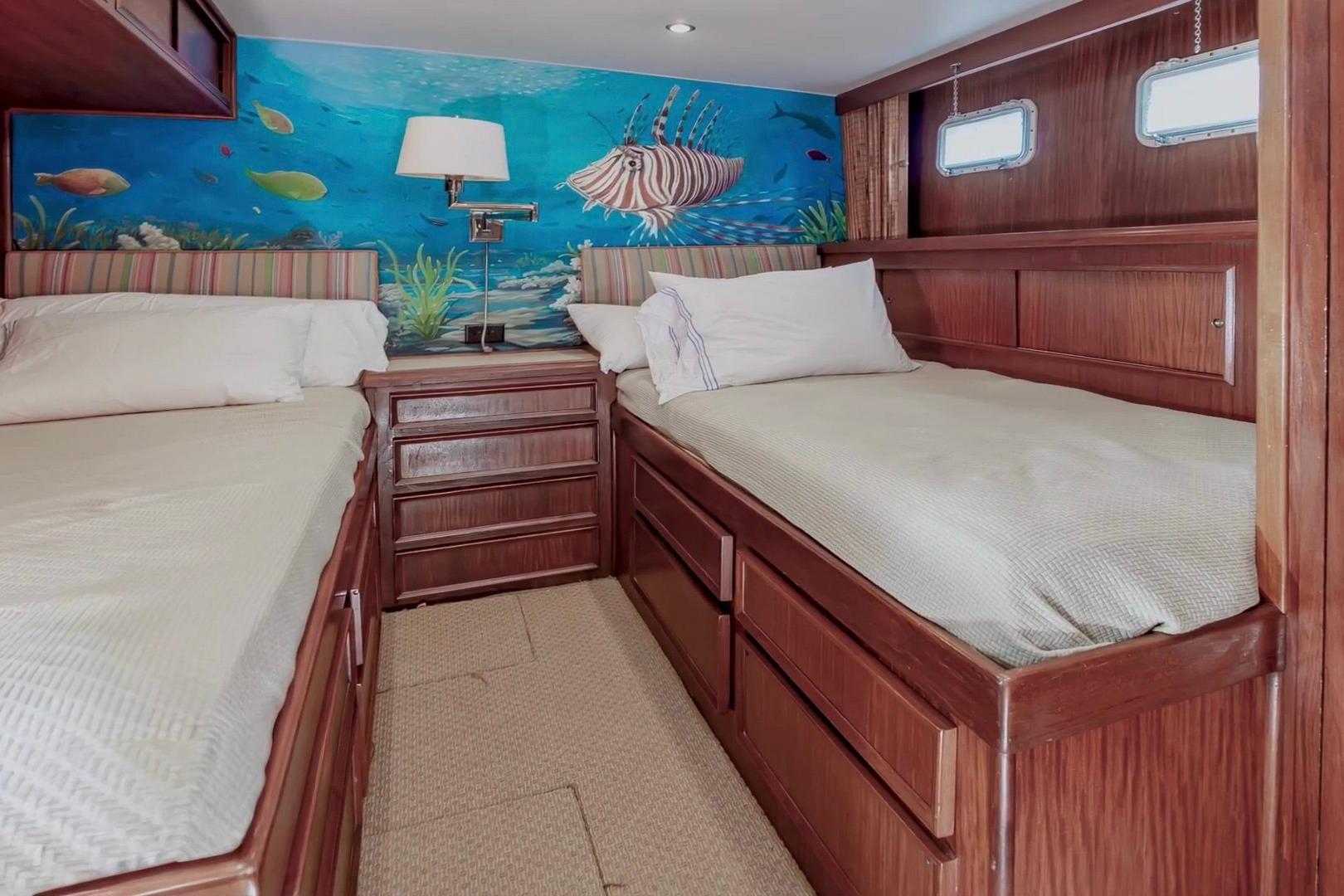 Cozy twin cabin with ocean-themed mural in 1980 Hatteras 70 Motor Yacht.