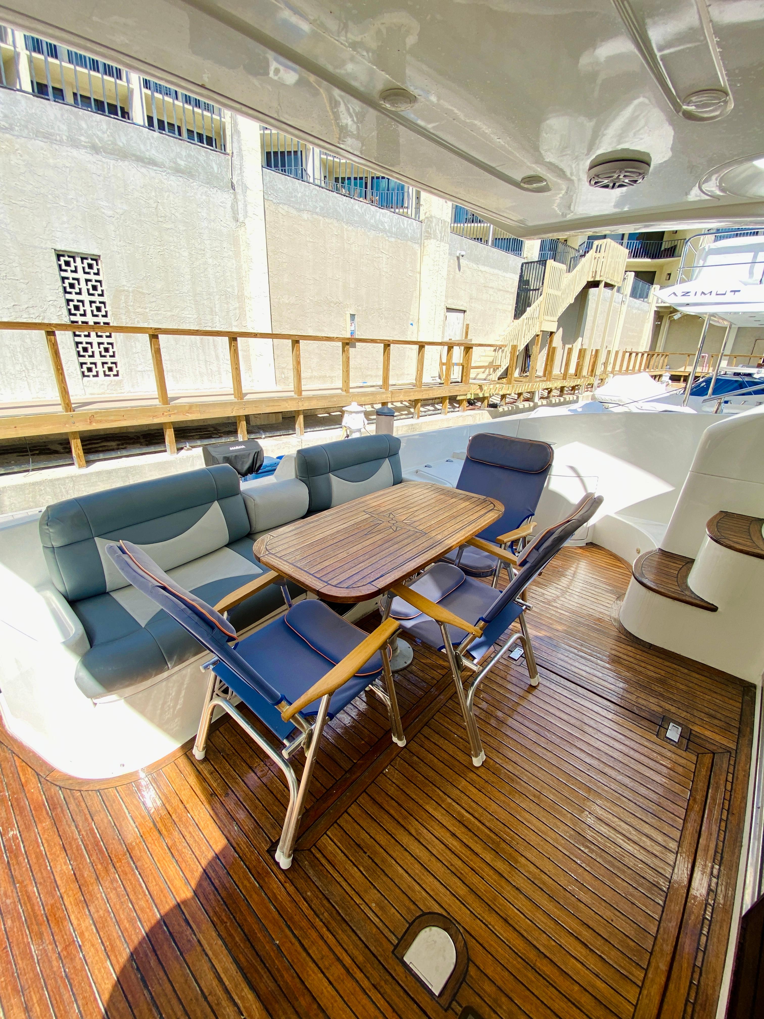 2002 Azimut 55 yacht deck with seating and wooden table.